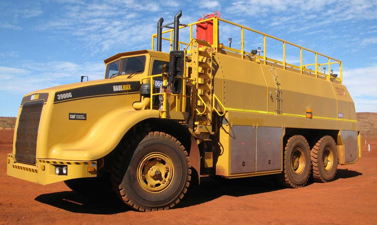 A Large Yellow Truck Is Parked On A Dirt Road