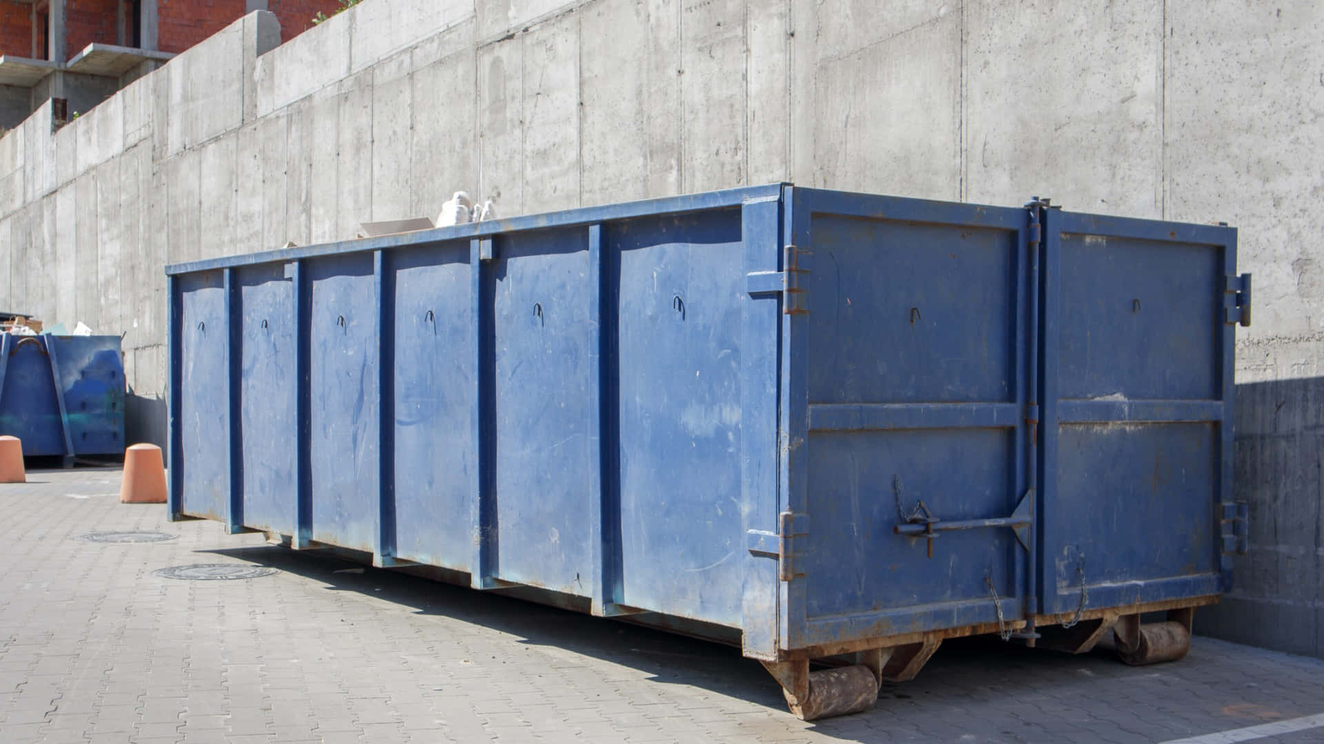 A Blue Container Sitting On The Side Of A Concrete Wall