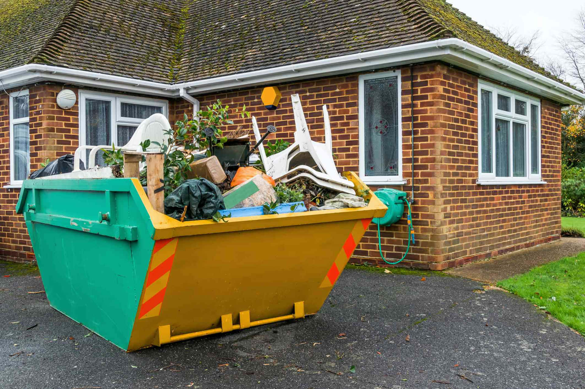 A Green Garbage Bin In Front Of A House