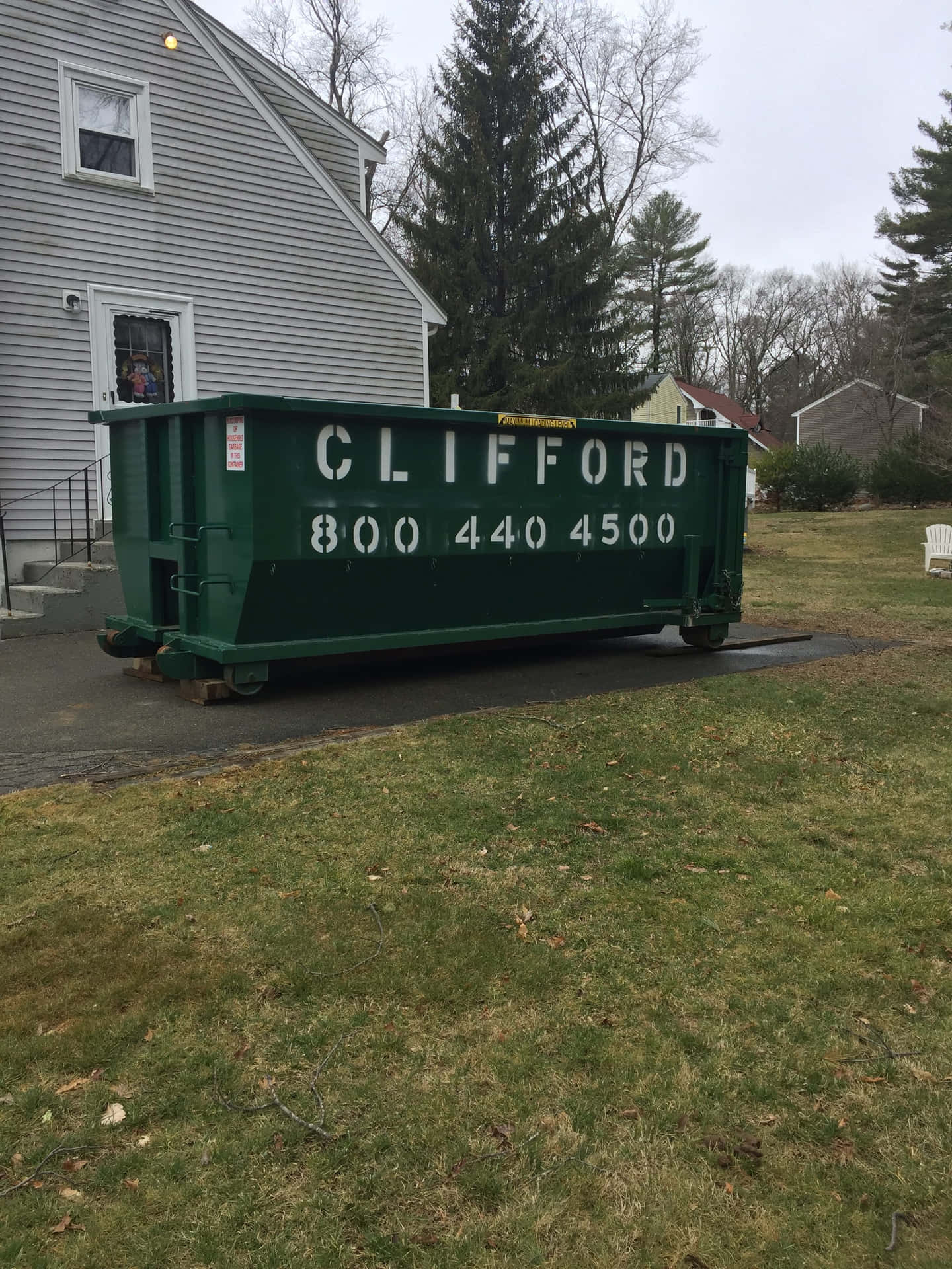 A Green Dumpster Parked In Front Of A House