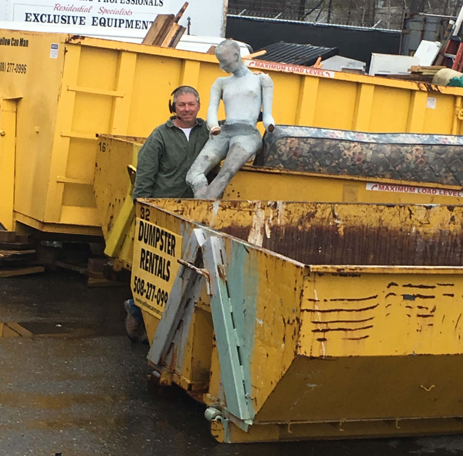 A Man Standing Next To A Yellow Dump Truck