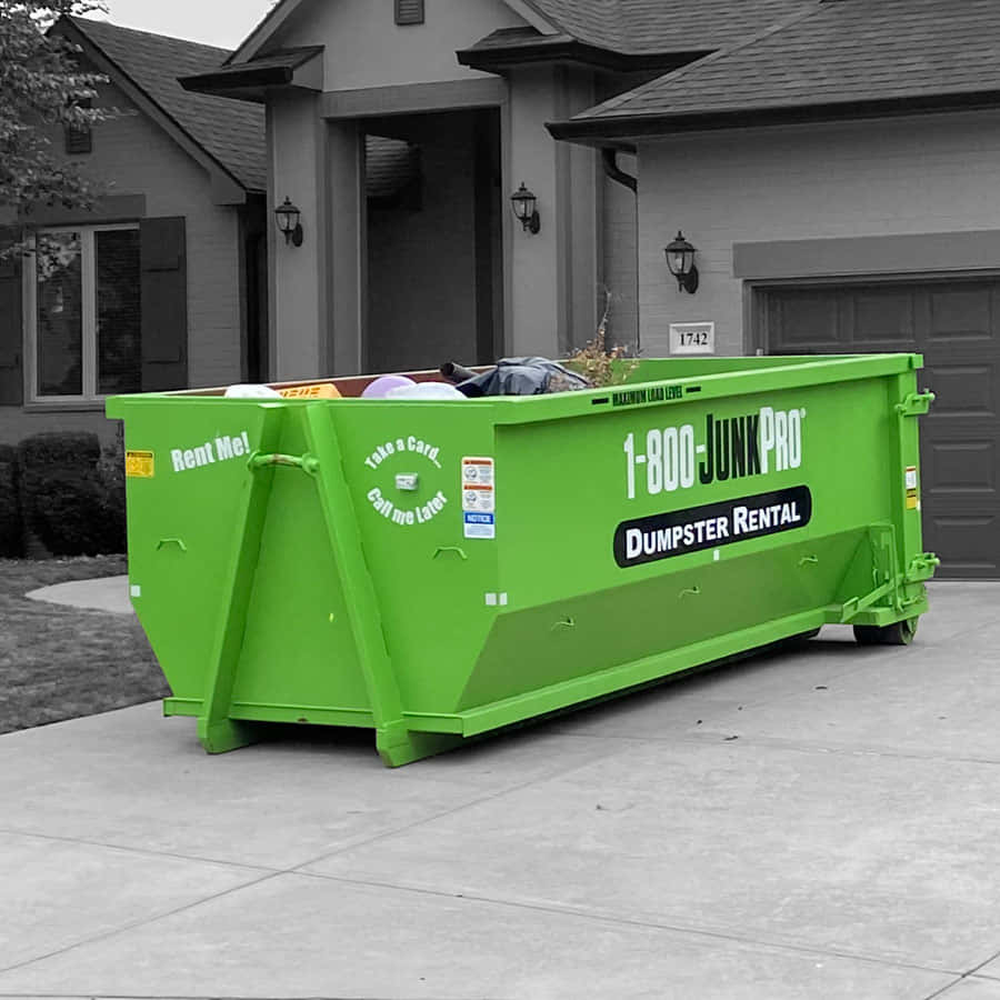 A Green Dumpster Sitting In Front Of A House