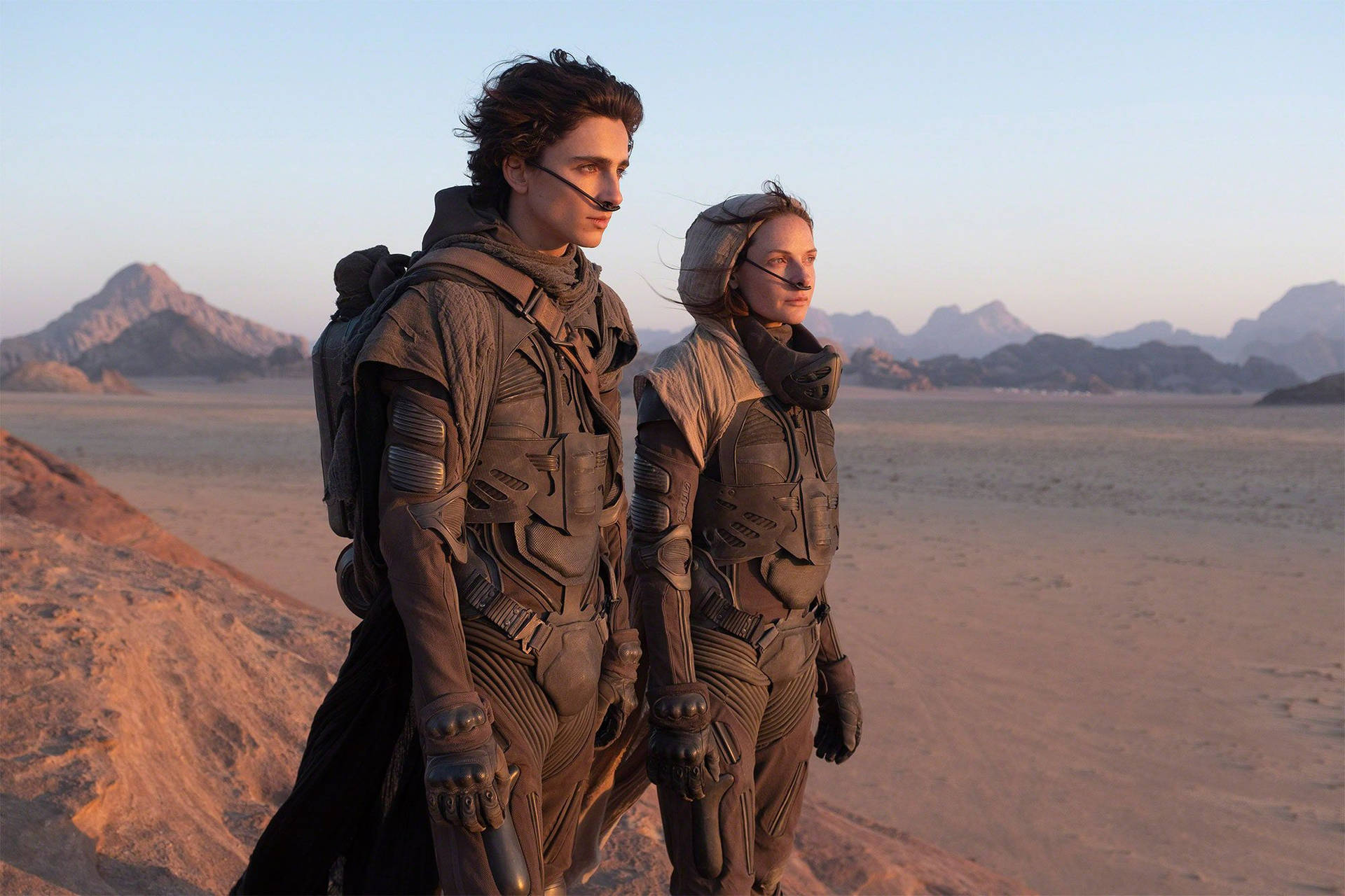Two People In Space Suits Standing In The Desert Wallpaper