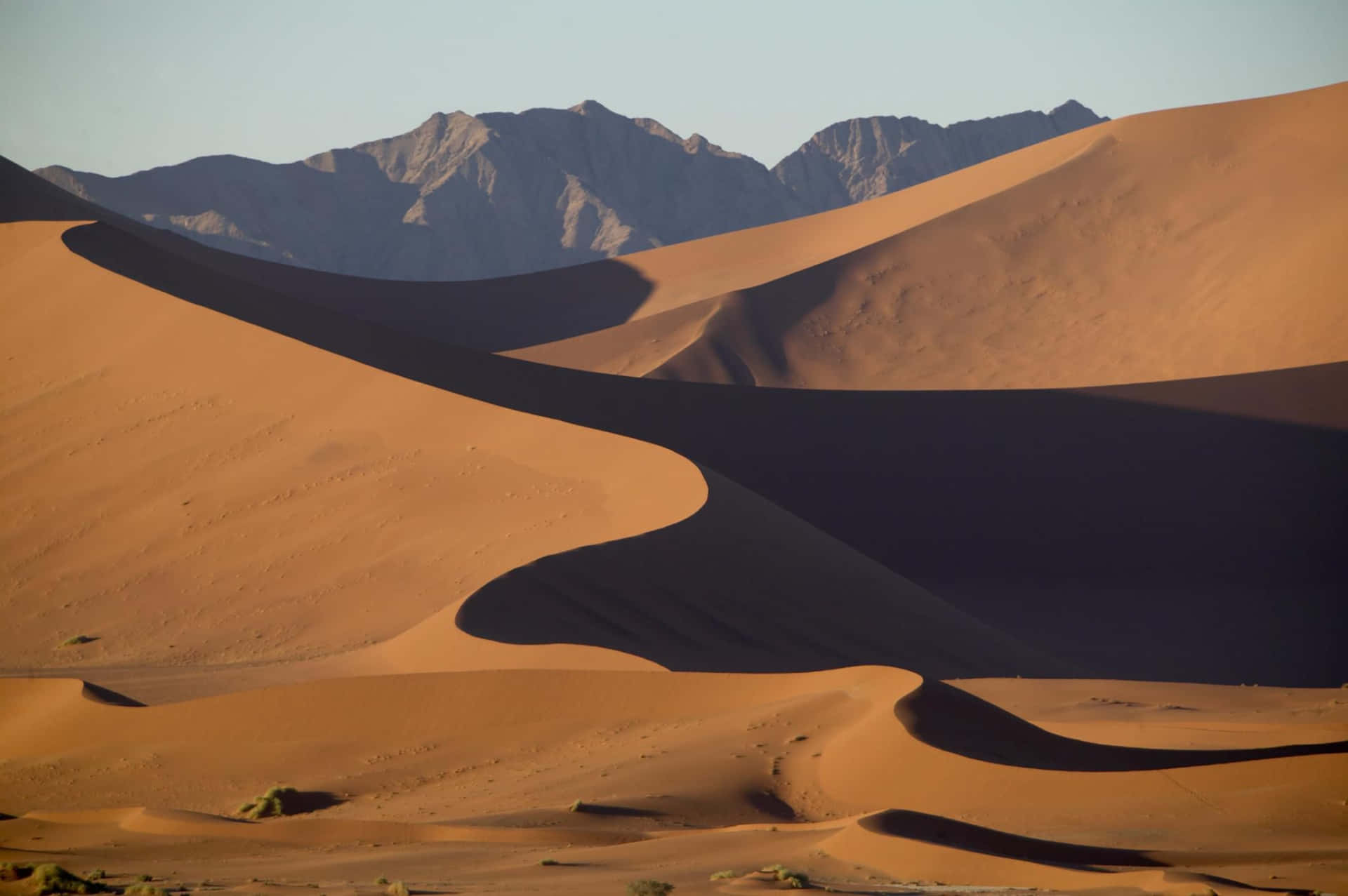 A Desert Landscape With Sand Dunes And Mountains