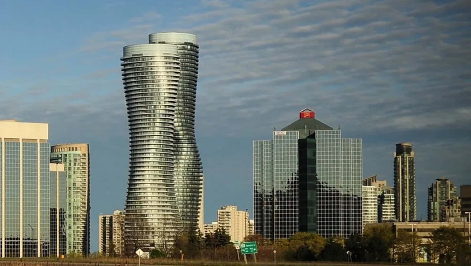 Dusk Falls Over The Bustling Cityscape Of Mississauga With Illuminated Skyscrapers Mirrored On The Lake's Surface Wallpaper