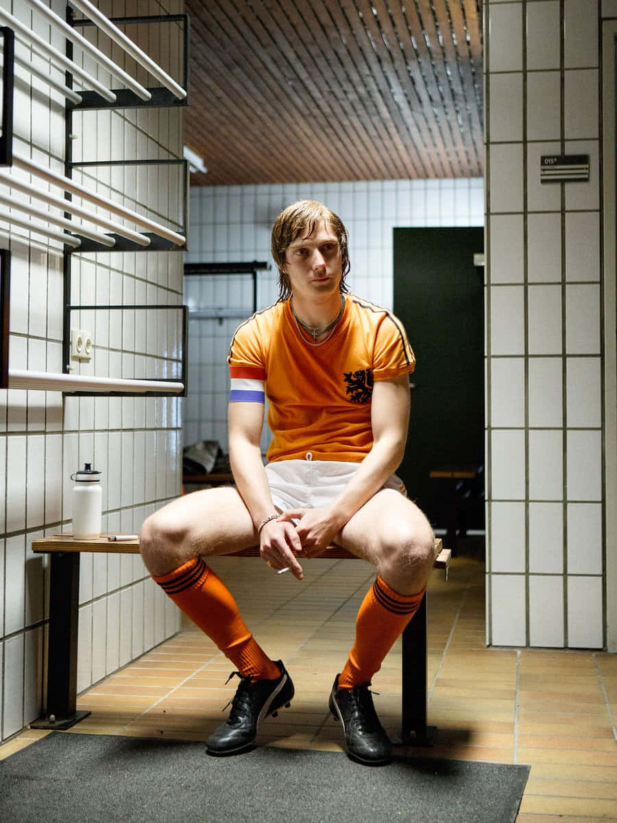 Niederländischerfußballer Johan Cruyff Sitzt Auf Der Bank Wallpaper