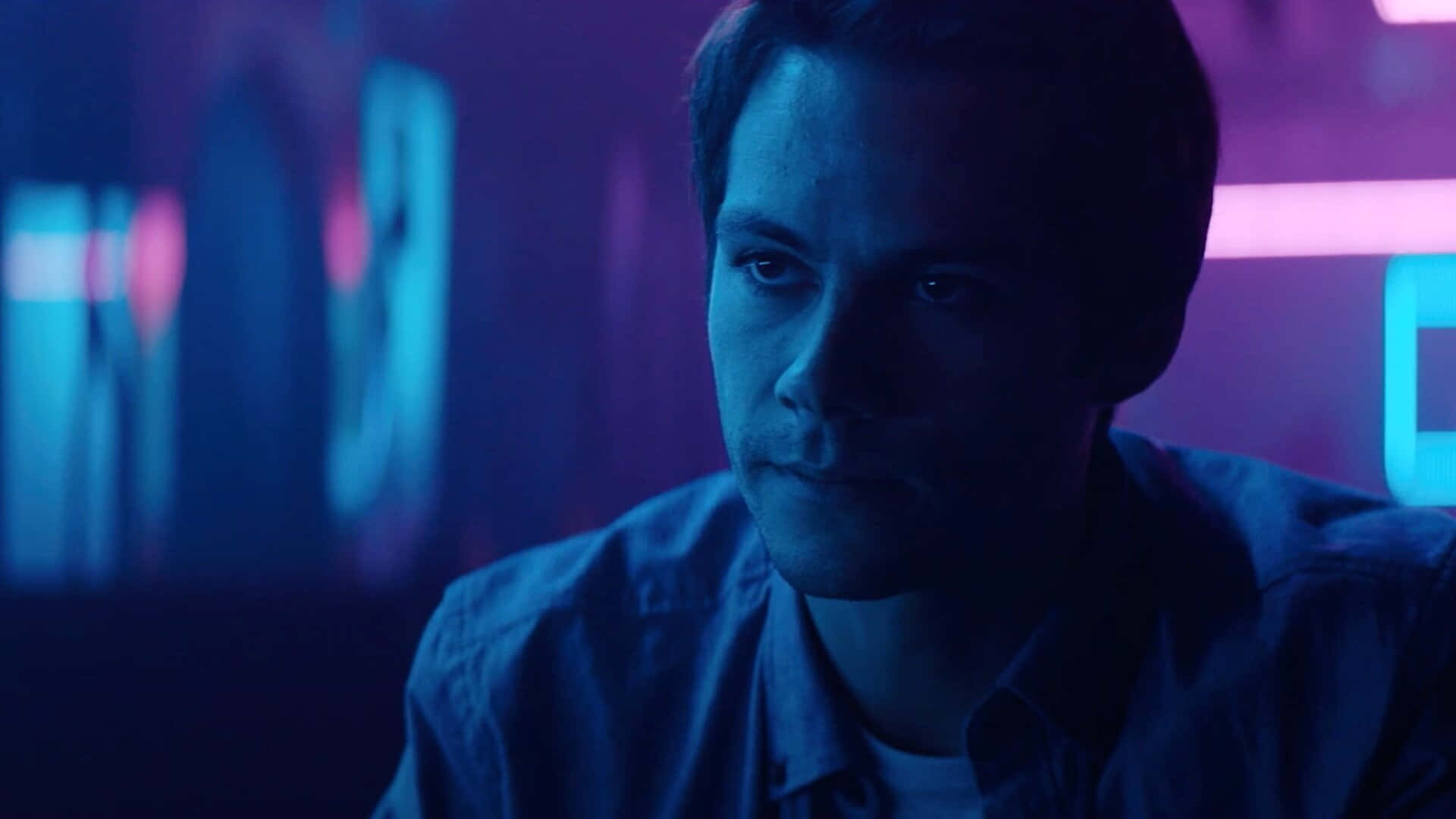 A Man In A Blue Shirt Is Staring At A Neon Light Wallpaper