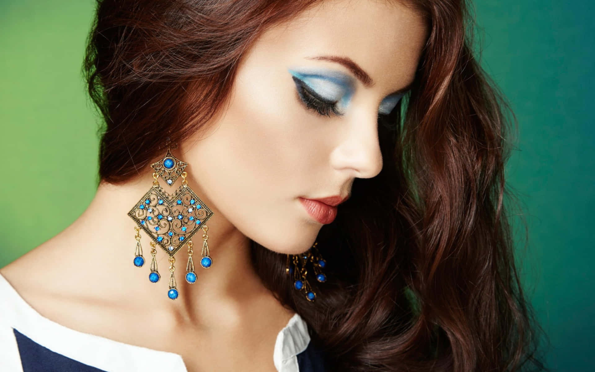 A Beautiful Woman With Blue Earrings And Blue Eye Makeup