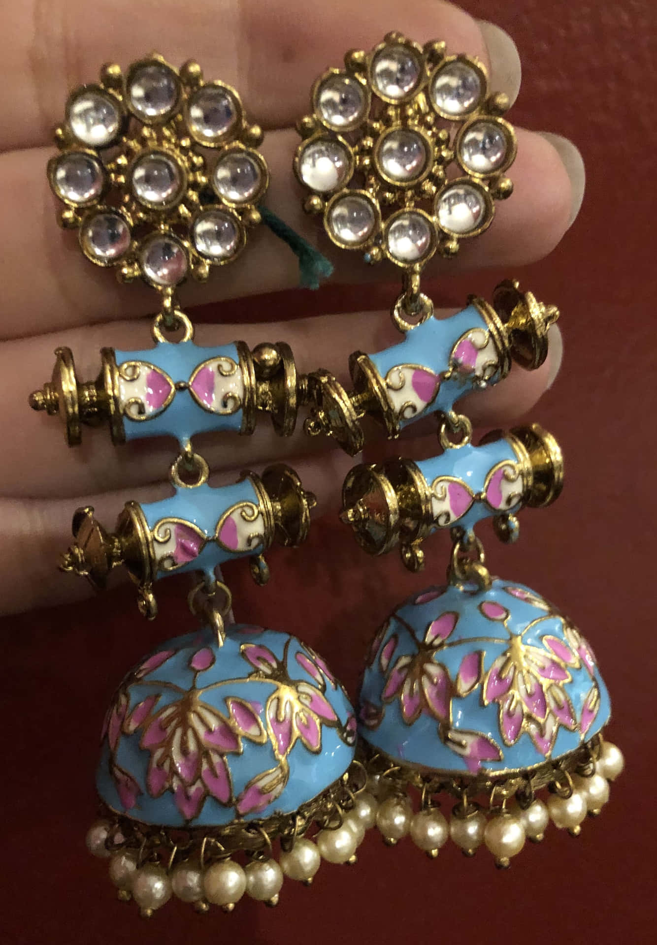 A Person Holding A Pair Of Blue Jhumka Earrings