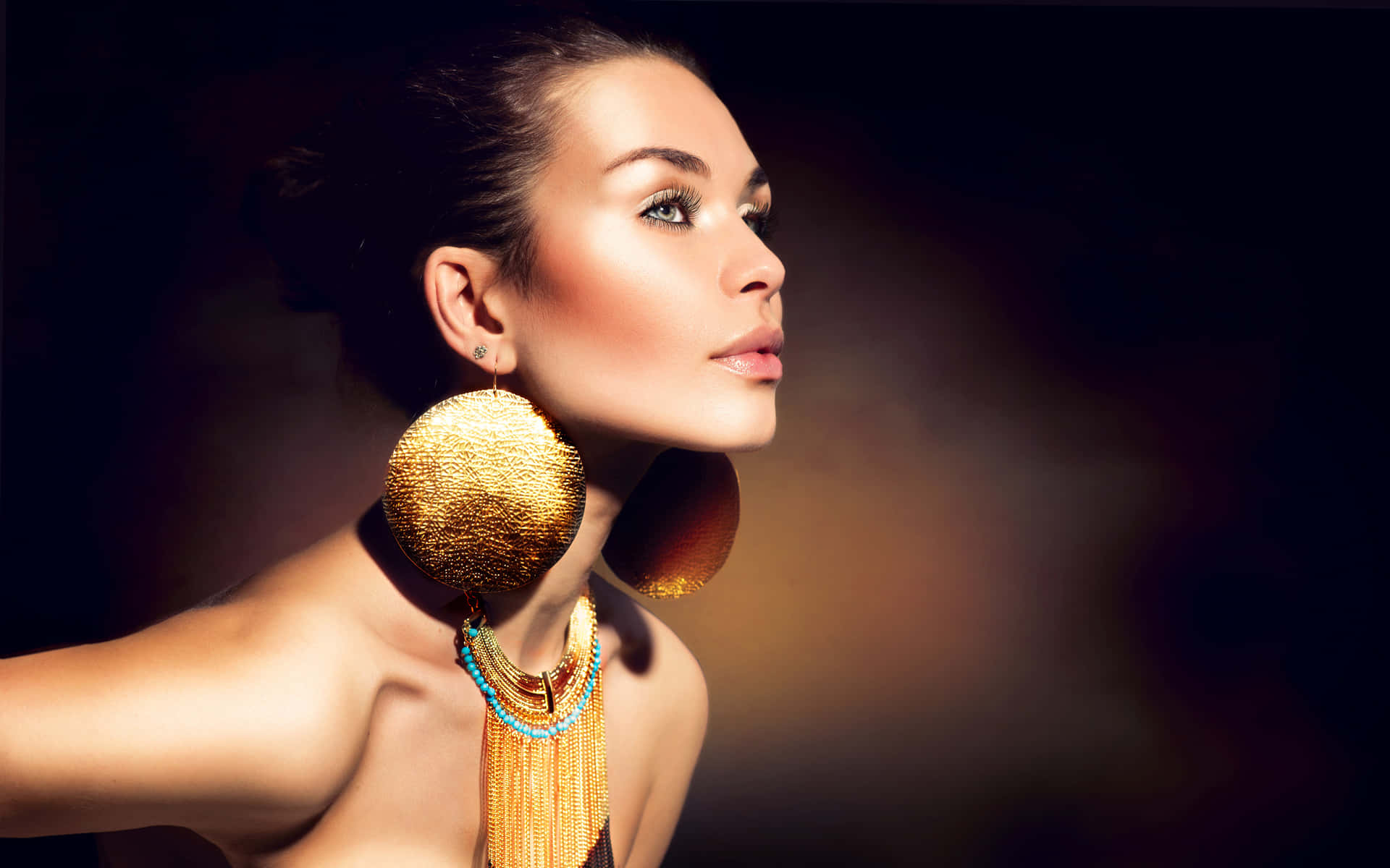 a woman wearing gold earrings and a necklace