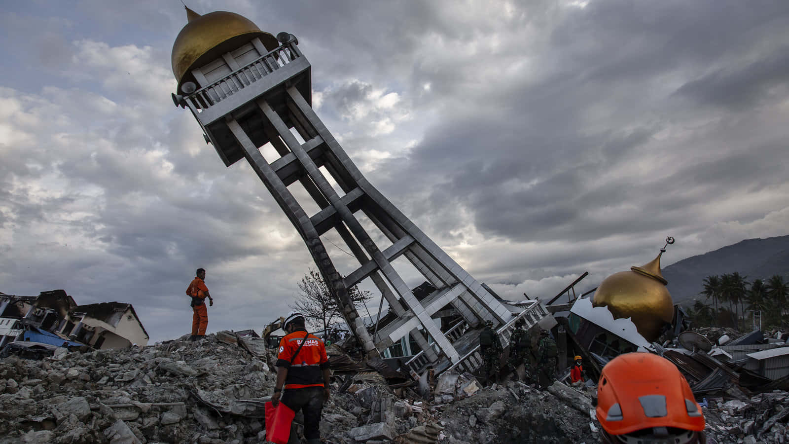 A Group Of People Are Standing Near A Tower That Has Been Destroyed