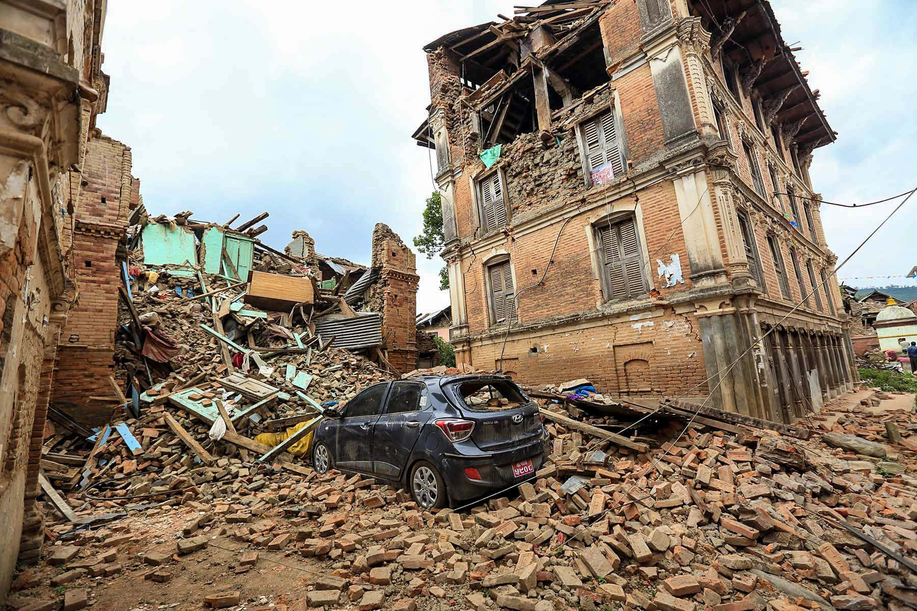 A Car Is Parked In Front Of A Building That Has Been Destroyed