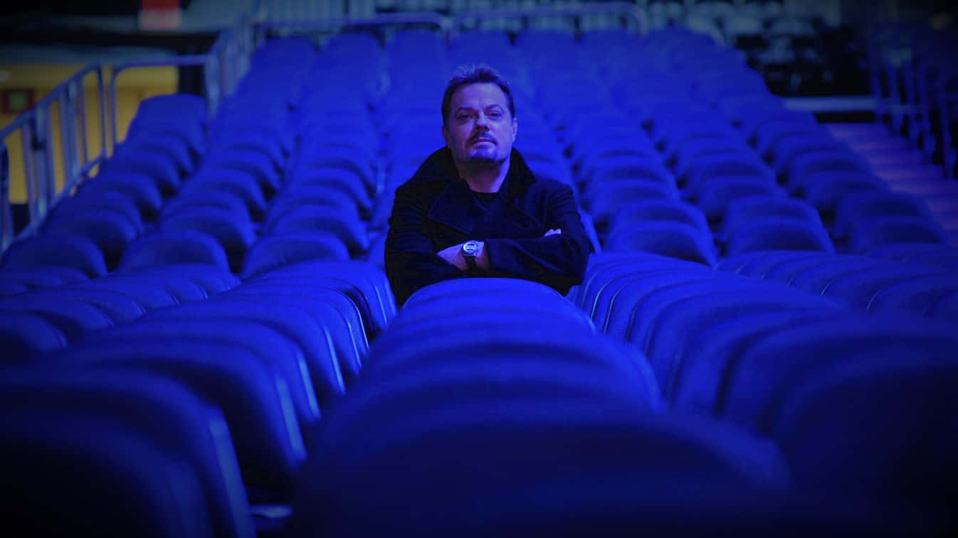Eddie Izzard posing on stage during a live performance Wallpaper