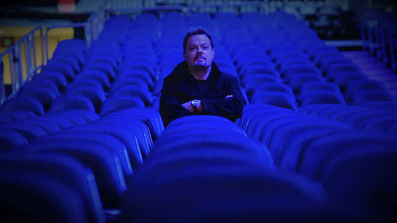 Eddie Izzard Poseert Op Het Podium Tijdens Een Live Optreden Achtergrond