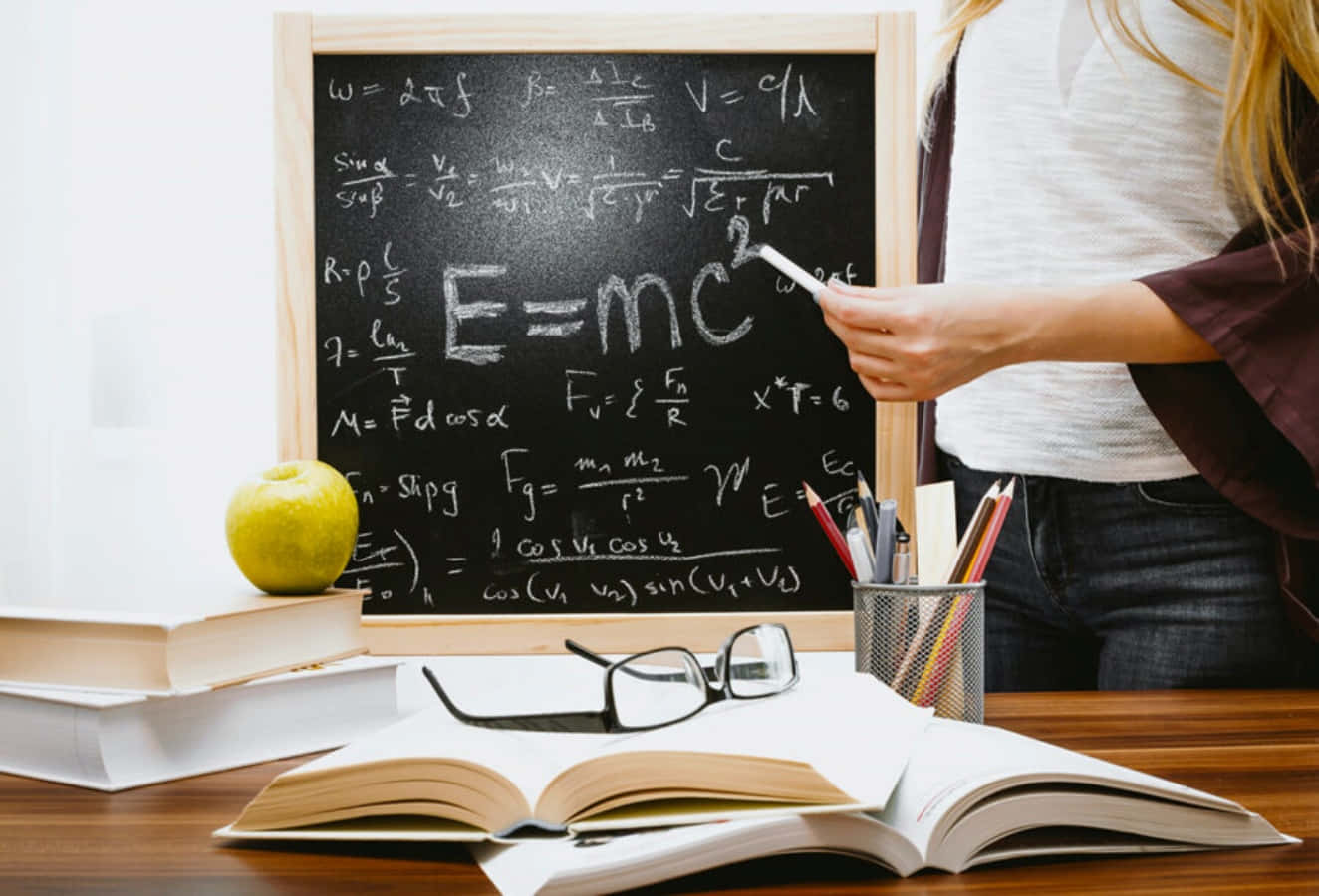 A Woman Is Standing In Front Of A Blackboard With A Book And A Calculator