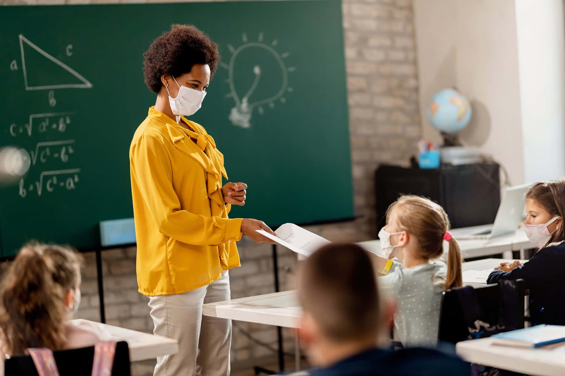 Lærerenbærer En Maske Foran Børnene I Klasseværelset.