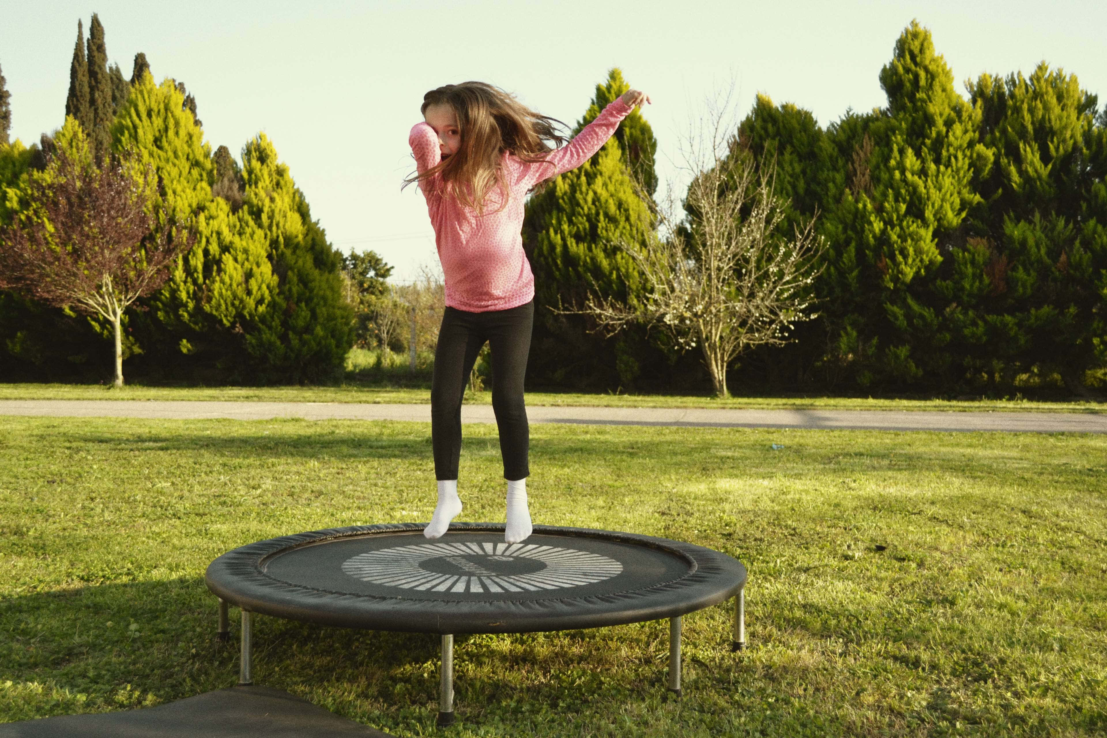 Een Kind Dat Vrolijk Springt Op Een Trampoline Onder Een Heldere Lucht. Achtergrond