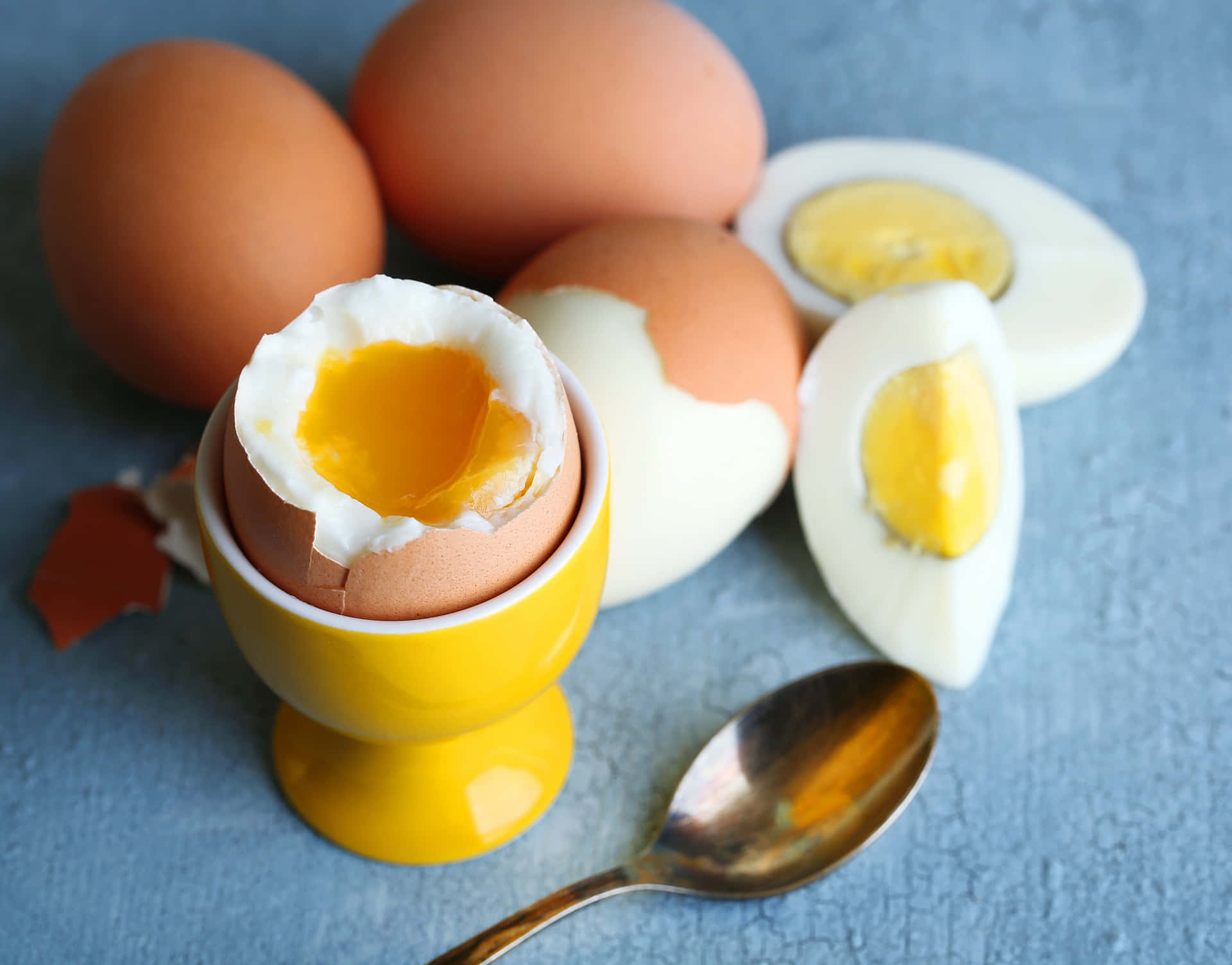 A Yellow Egg Cup With A Spoon And A Broken Egg