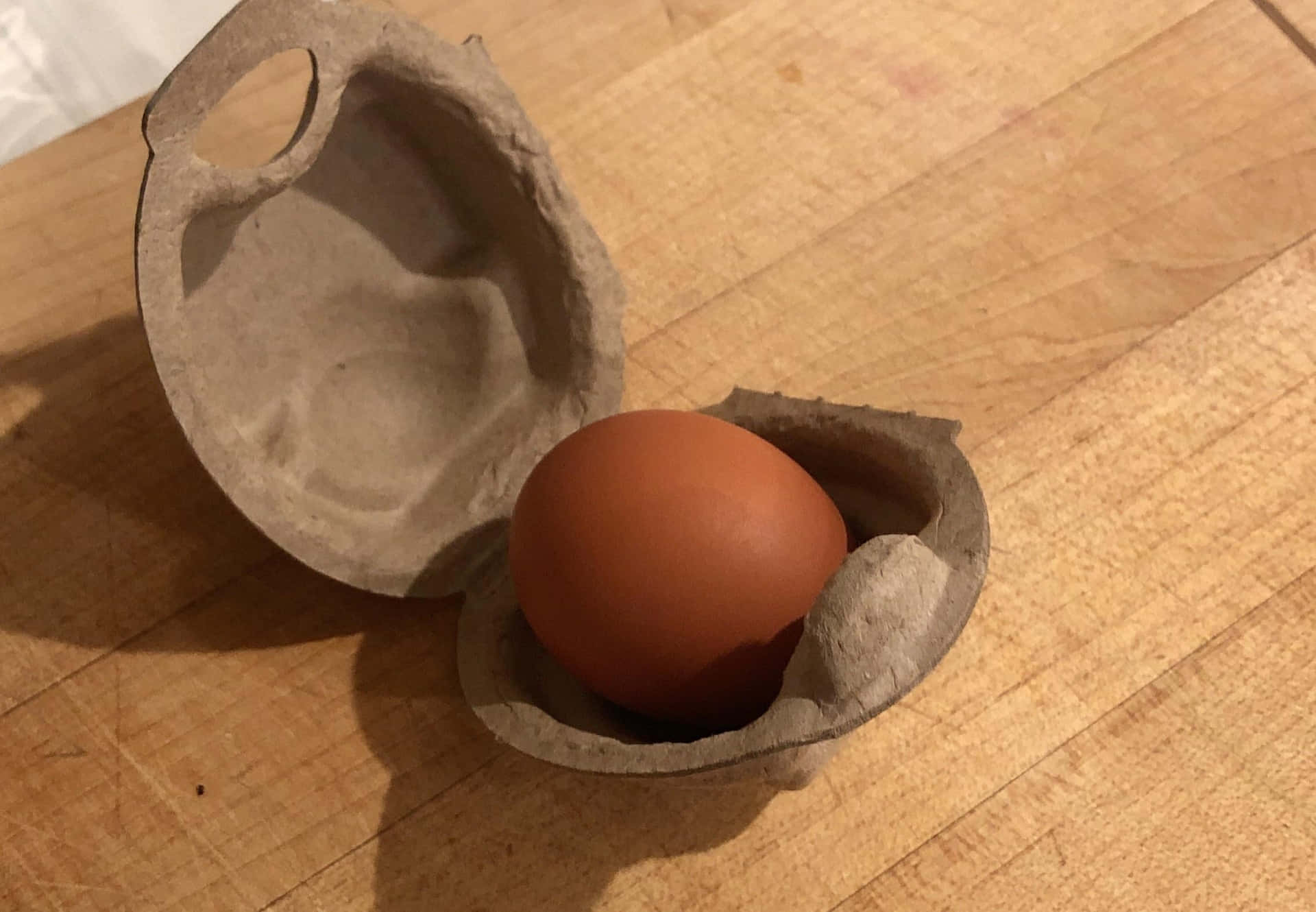 An Egg In A Cardboard Box On A Wooden Table