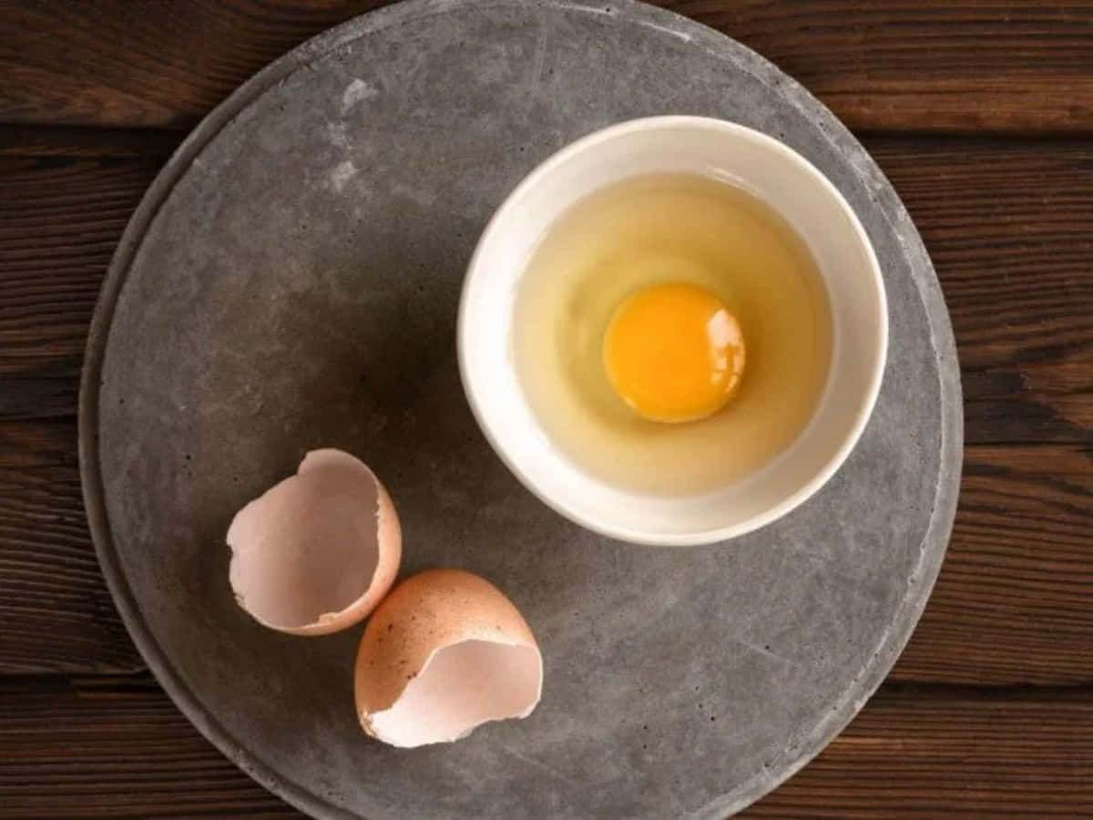 A Broken Egg On A Plate With A Cup Of Water