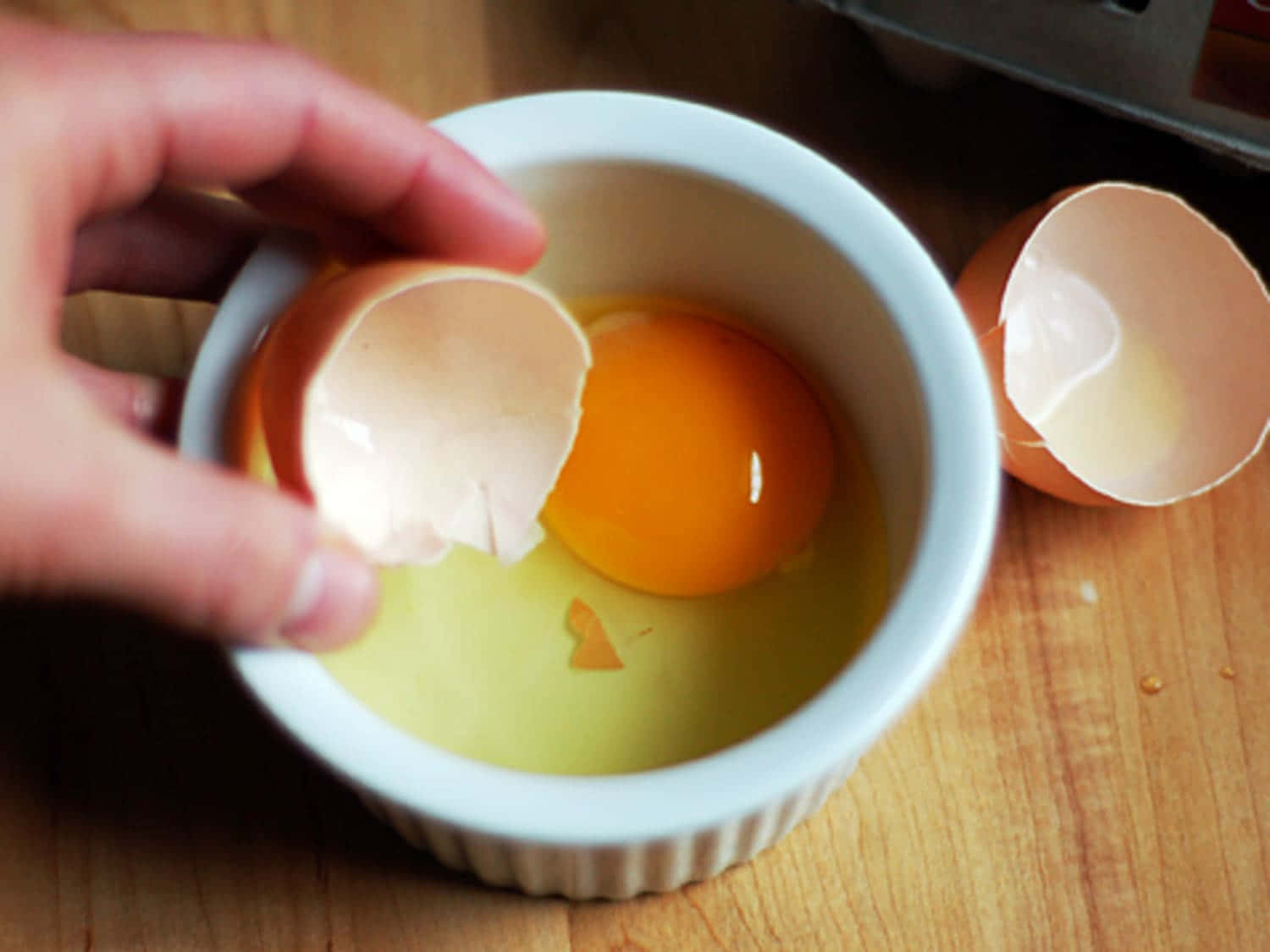 A cracked open eggshell showing a half-peeled yolk Wallpaper