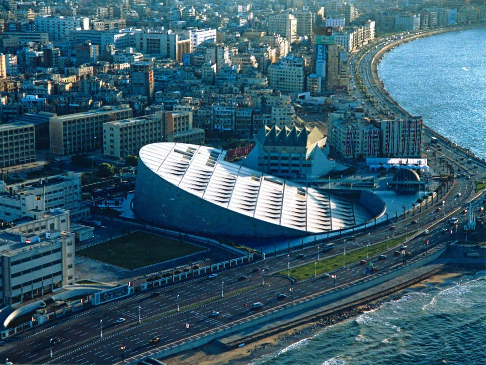 A Building With A Large Curved Roof Near The Ocean