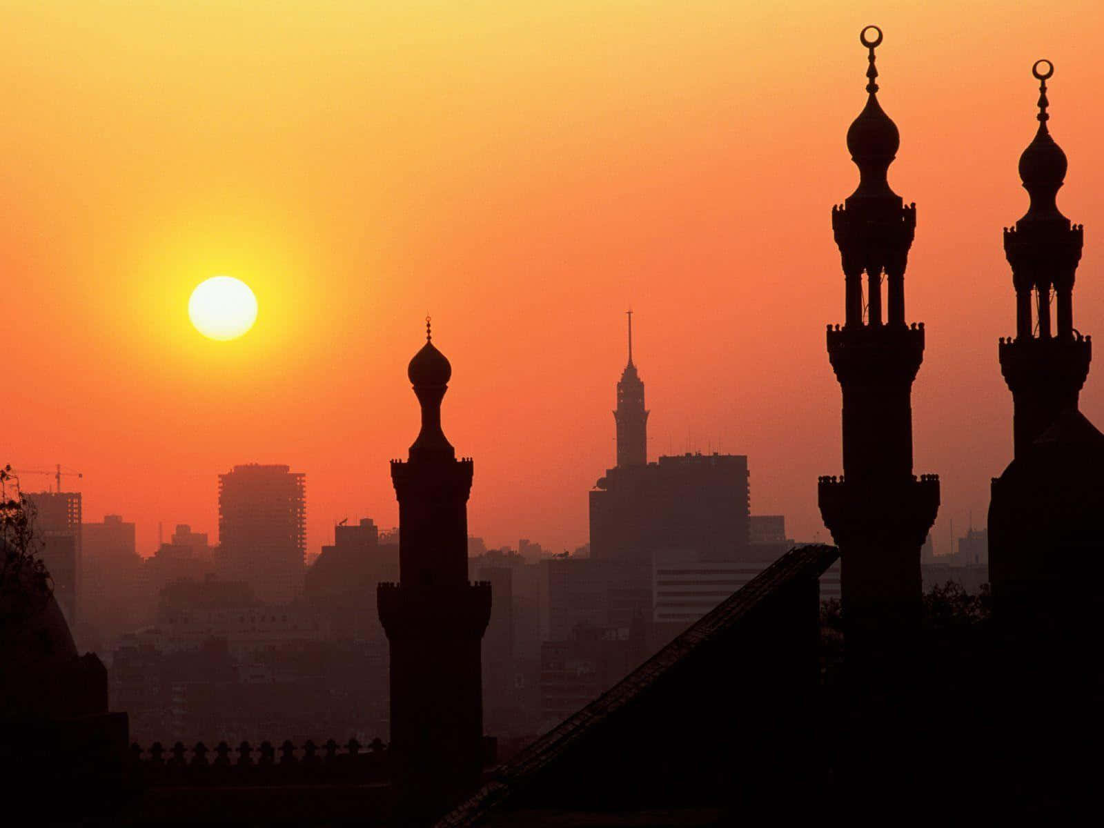 A Cityscape With Mosques And A Sun Setting Behind Them