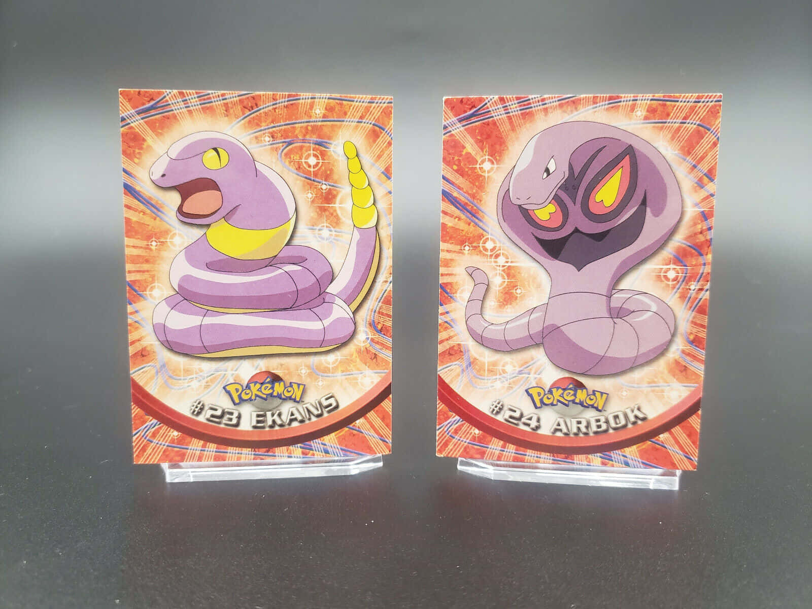 Ekans And Arbok Cards On Blurry Gray Background Wallpaper
