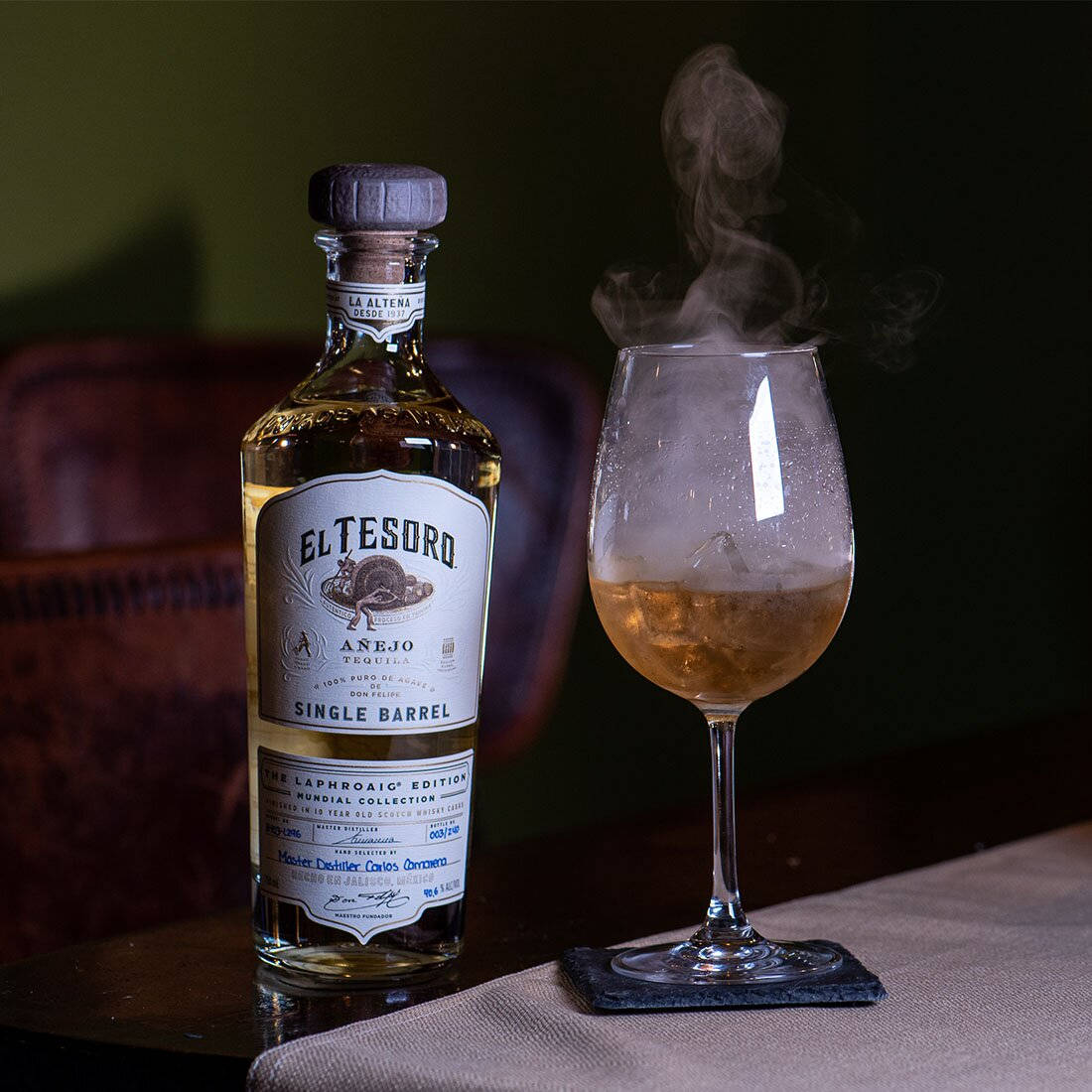 An exquisite bottle of El Tesoro Tequila showing its sophisticated charm in a smoky ambiance. Wallpaper