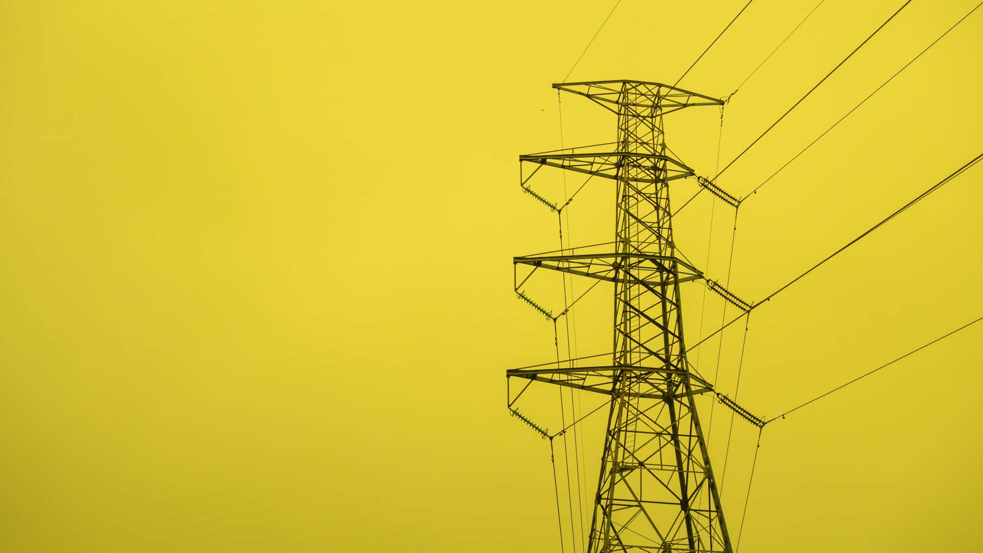 A High Voltage Pylon Against A Yellow Sky
