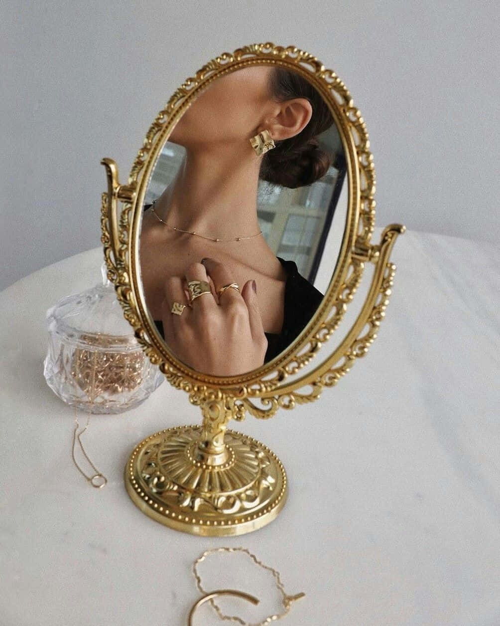 A Woman Is Holding A Gold Mirror And Jewelry Wallpaper