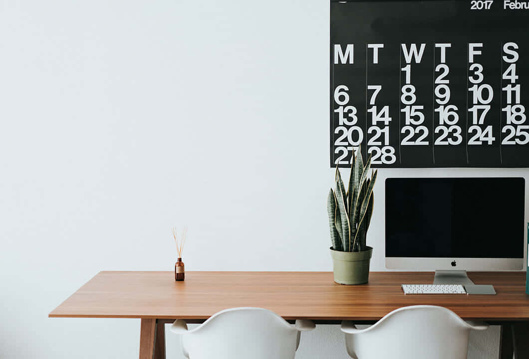 A Desk With A Calendar On It And A Computer