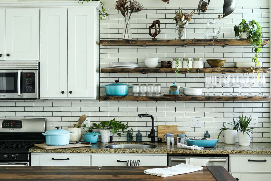 A Kitchen With White Cabinets And Wooden Shelves