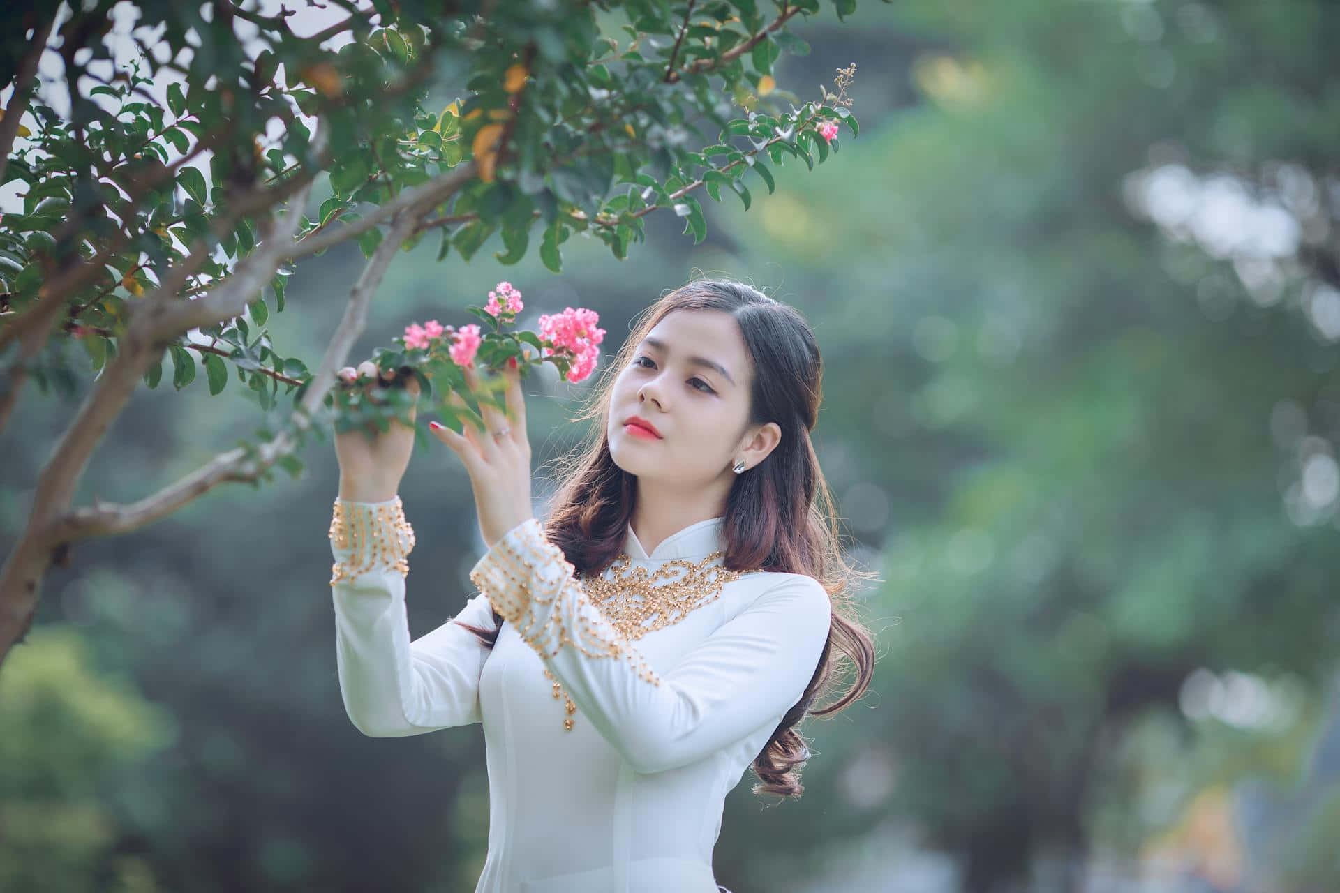 Elegant Woman Admiring Flowers Wallpaper