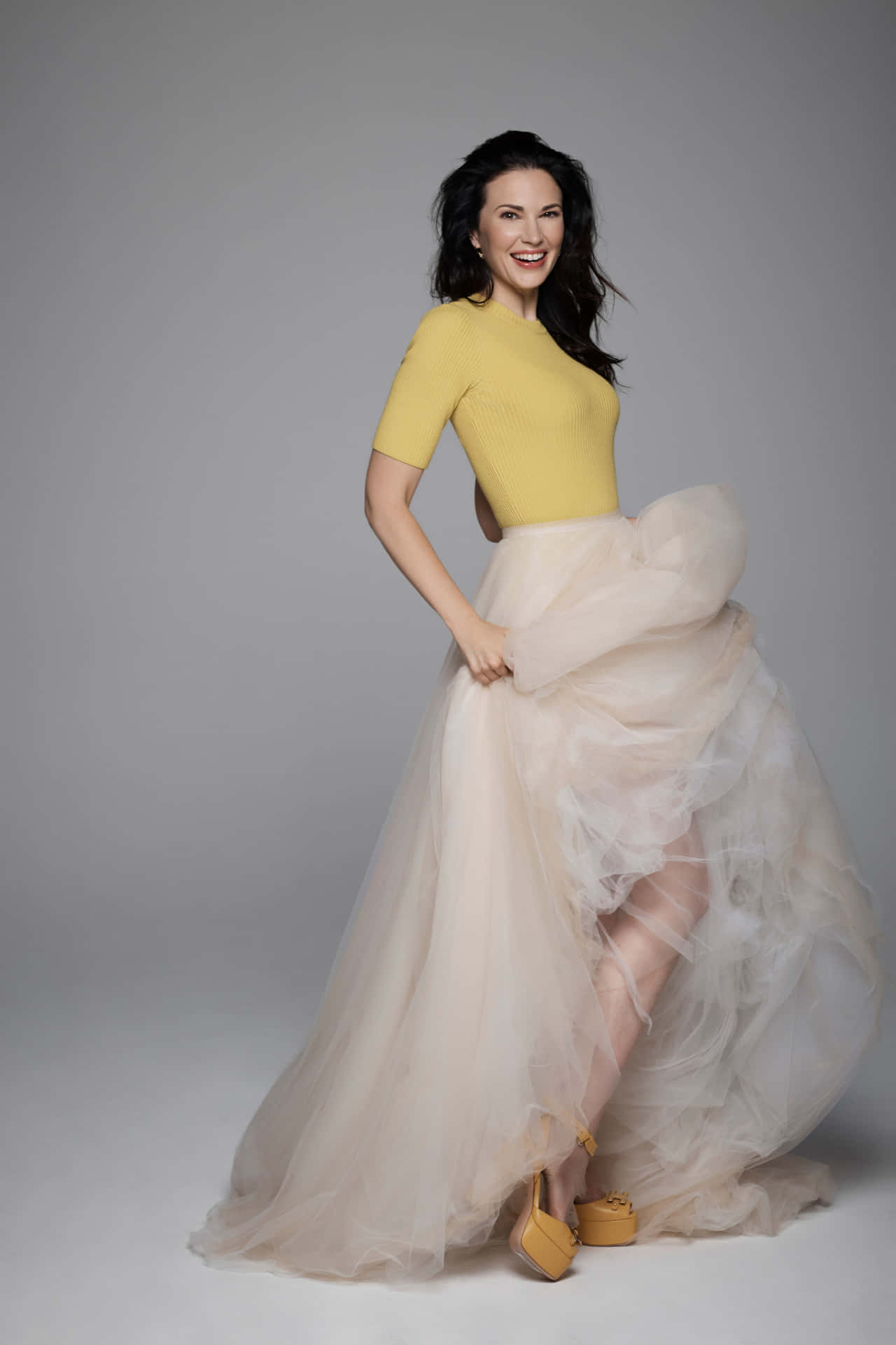 Elegant Womanin Yellow Topand Flowing Skirt Wallpaper
