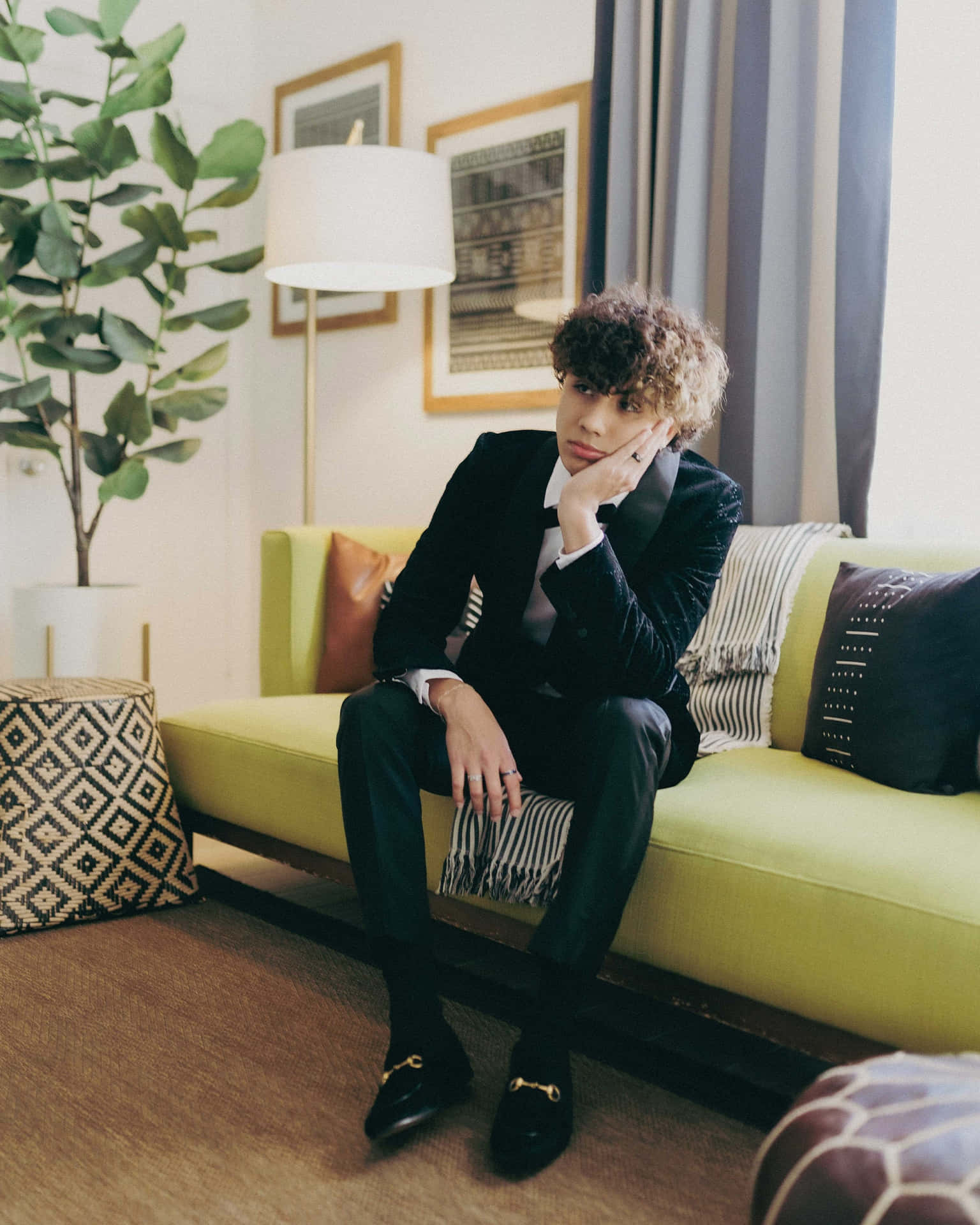 Elegant Young Man Seatedon Green Sofa Wallpaper