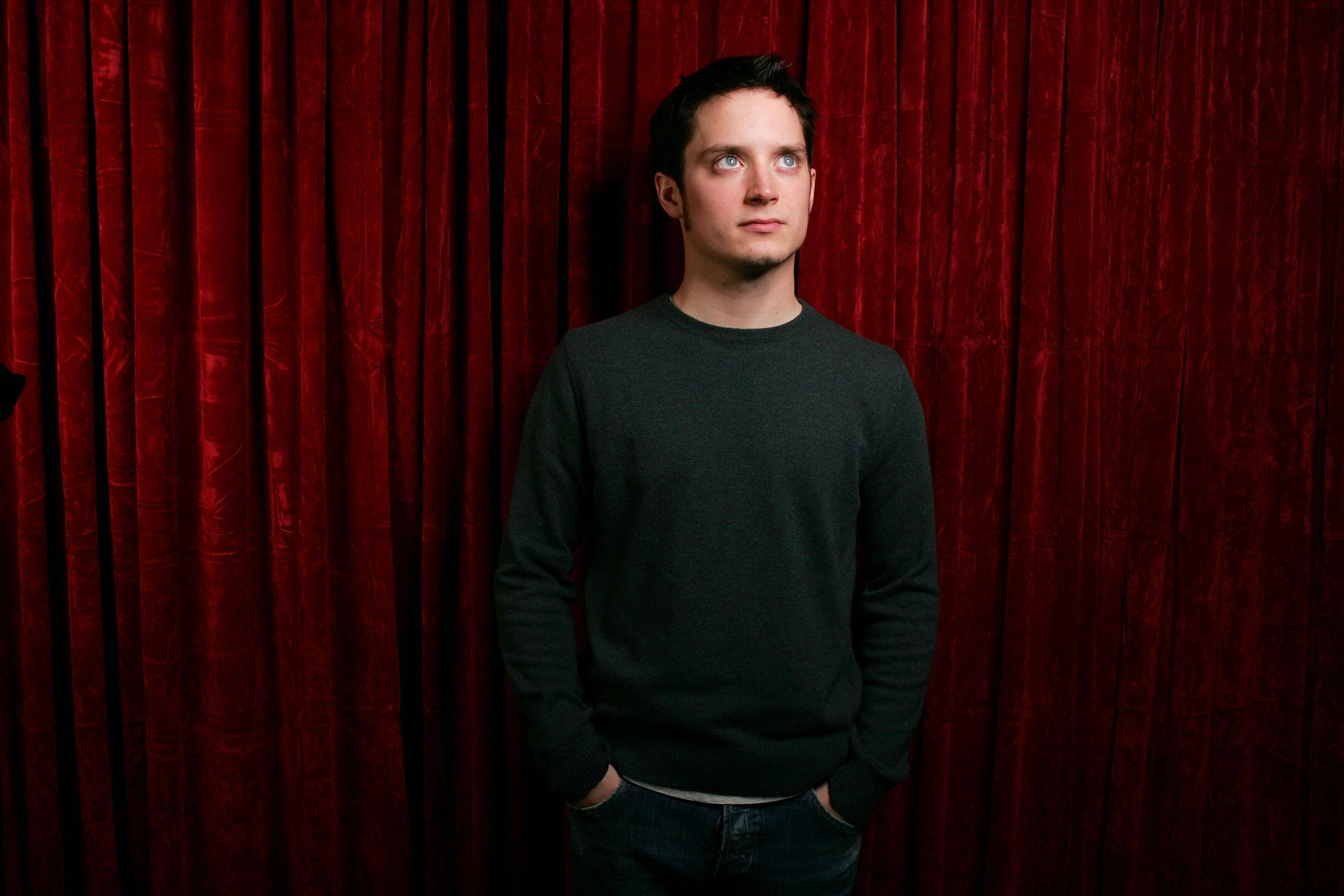 Elijah Wood In Front Of Red Curtain Wallpaper