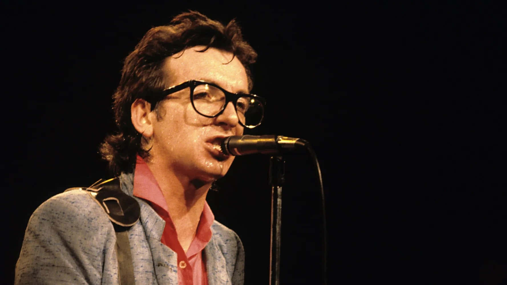 Elvis Costello Vintage 1979 Tapetet er inspireret af en gylden æra i britisk punk og new wave musik. Det har klassiske sort-hvide fotografier og blegne kulørde vektor grafik, designet til at bringe dit computer eller mobil skærm til live. Wallpaper