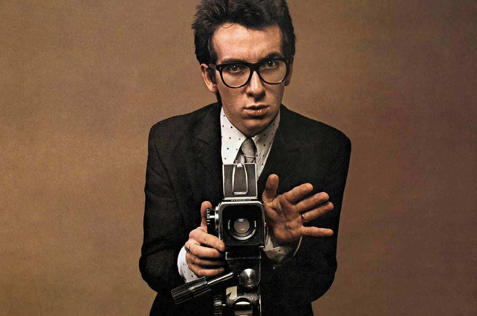 Elvis Costello With A Vintage Camera Wallpaper