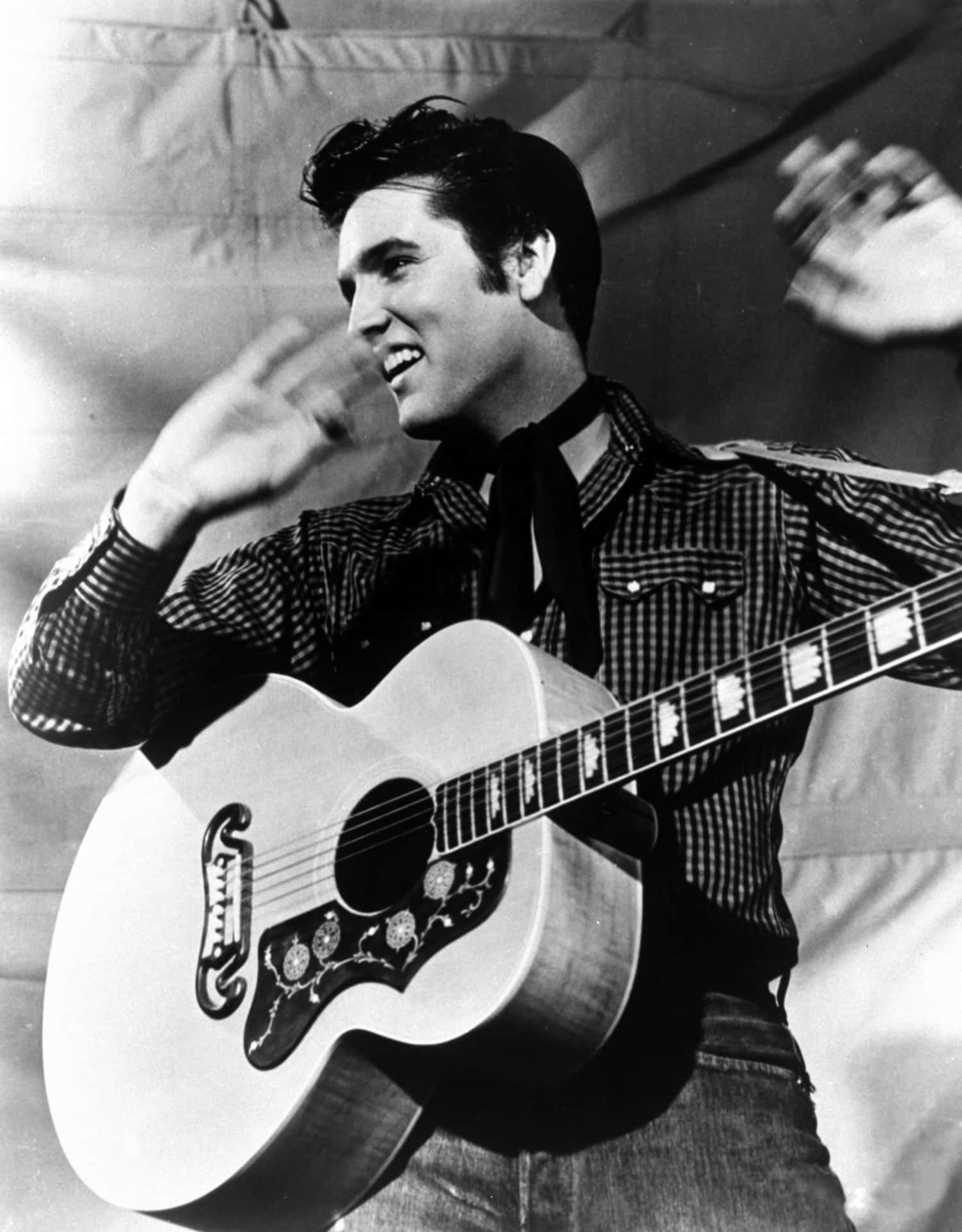 Elvis Presley Playing His Guitar With His Hands Up