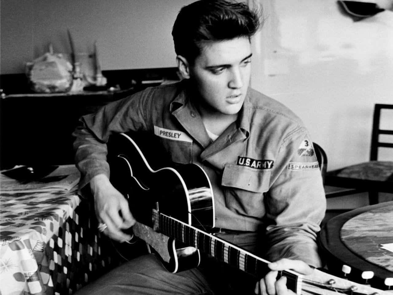 Elvispresley Spielt Gitarre In Einem Raum.