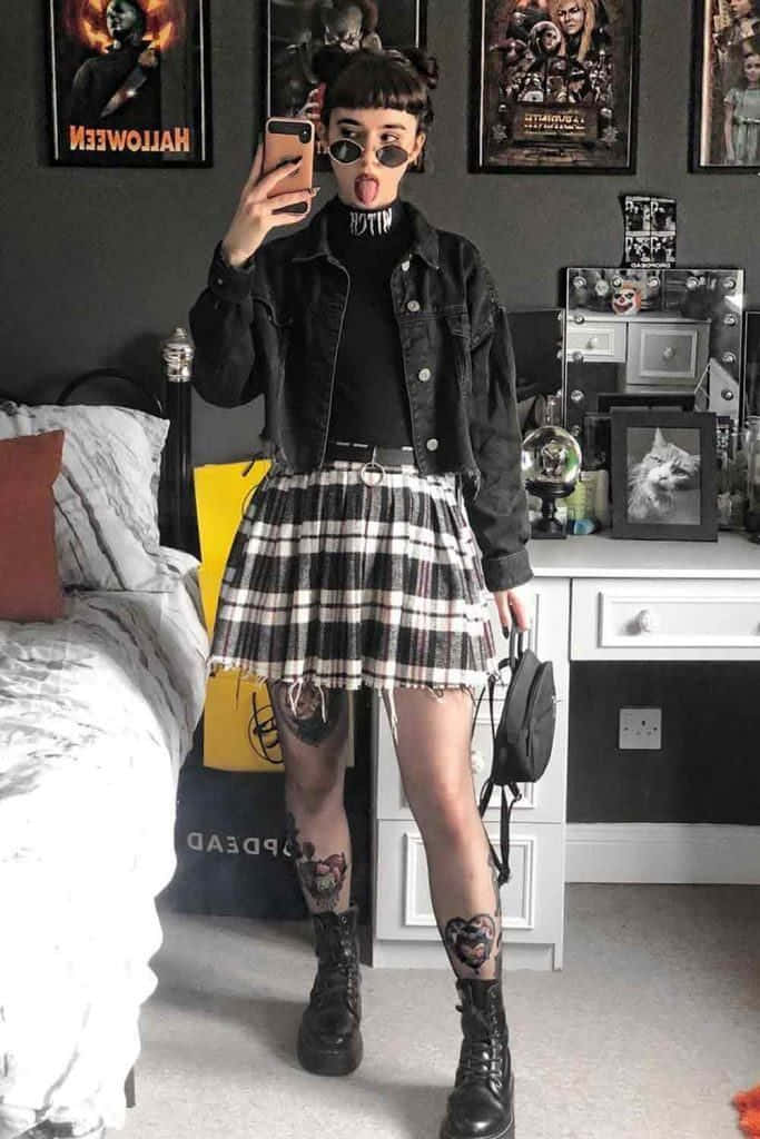 A Girl In A Plaid Skirt And Black Jacket Taking A Selfie