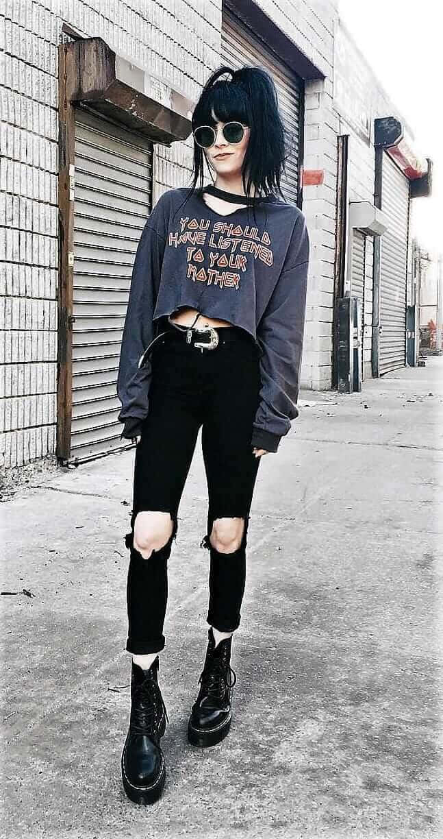 A Girl Wearing A Black Sweater And Ripped Jeans
