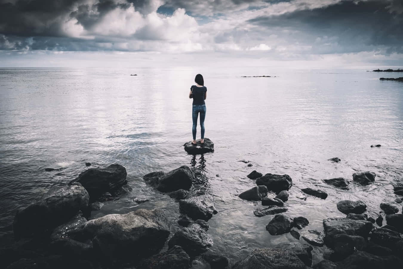 Woman Standing On Rocks In The Ocean