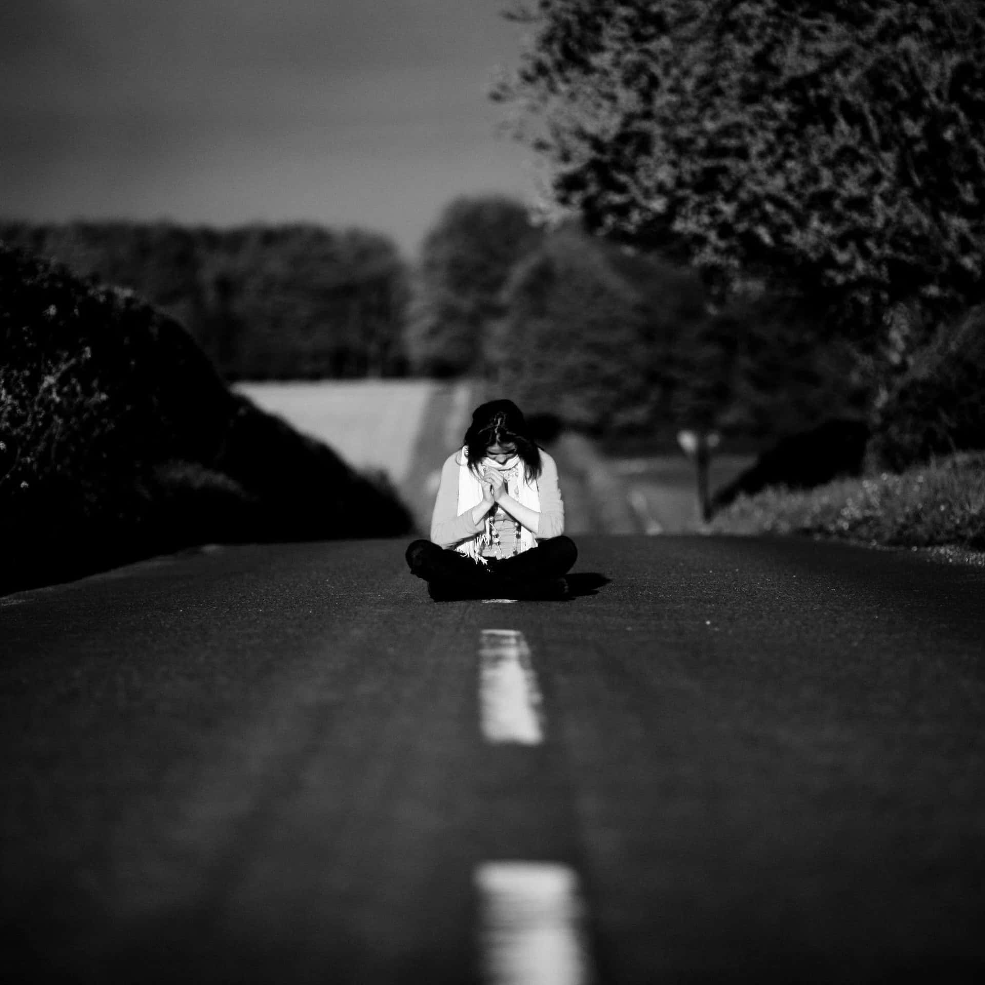 A Woman Sitting On The Road In Black And White