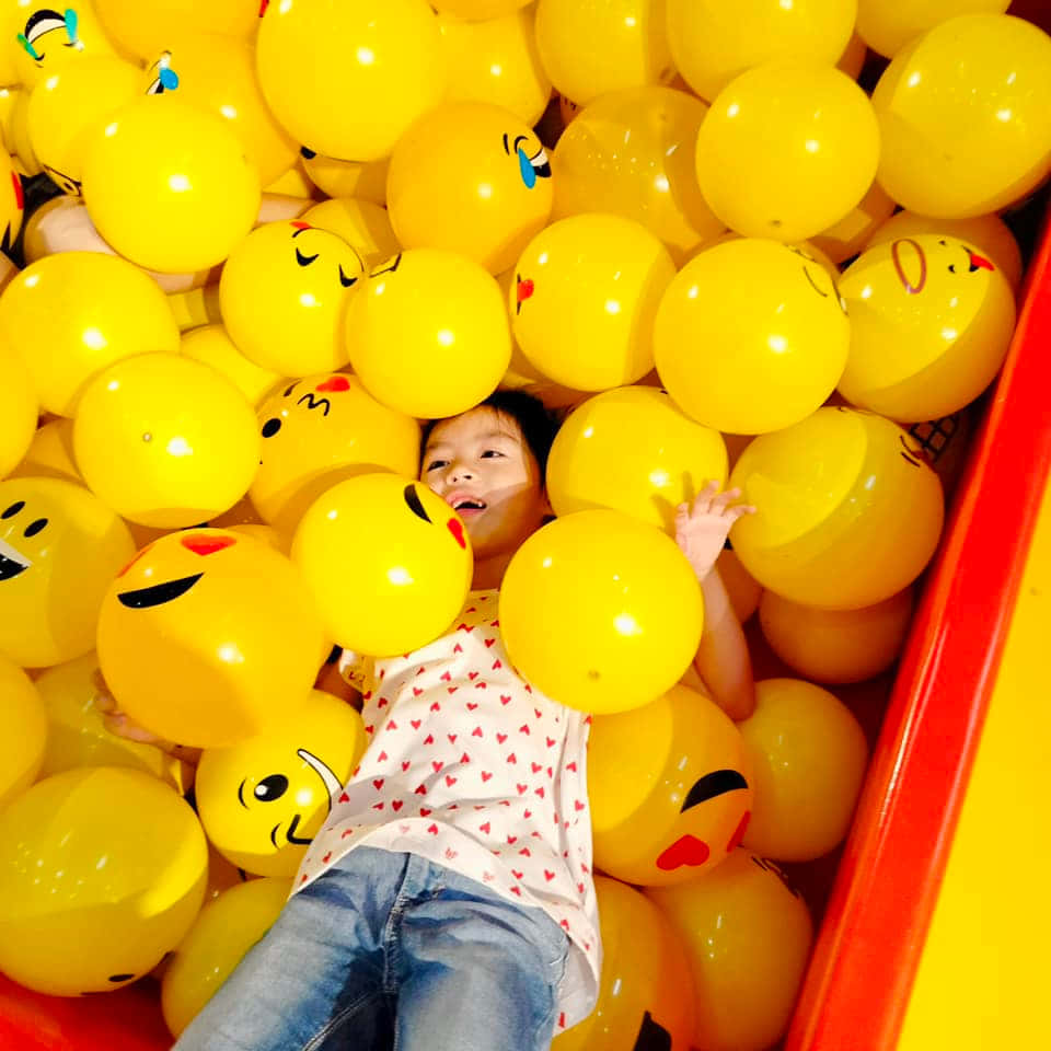 A Girl Is Laying In A Yellow Ball Pit