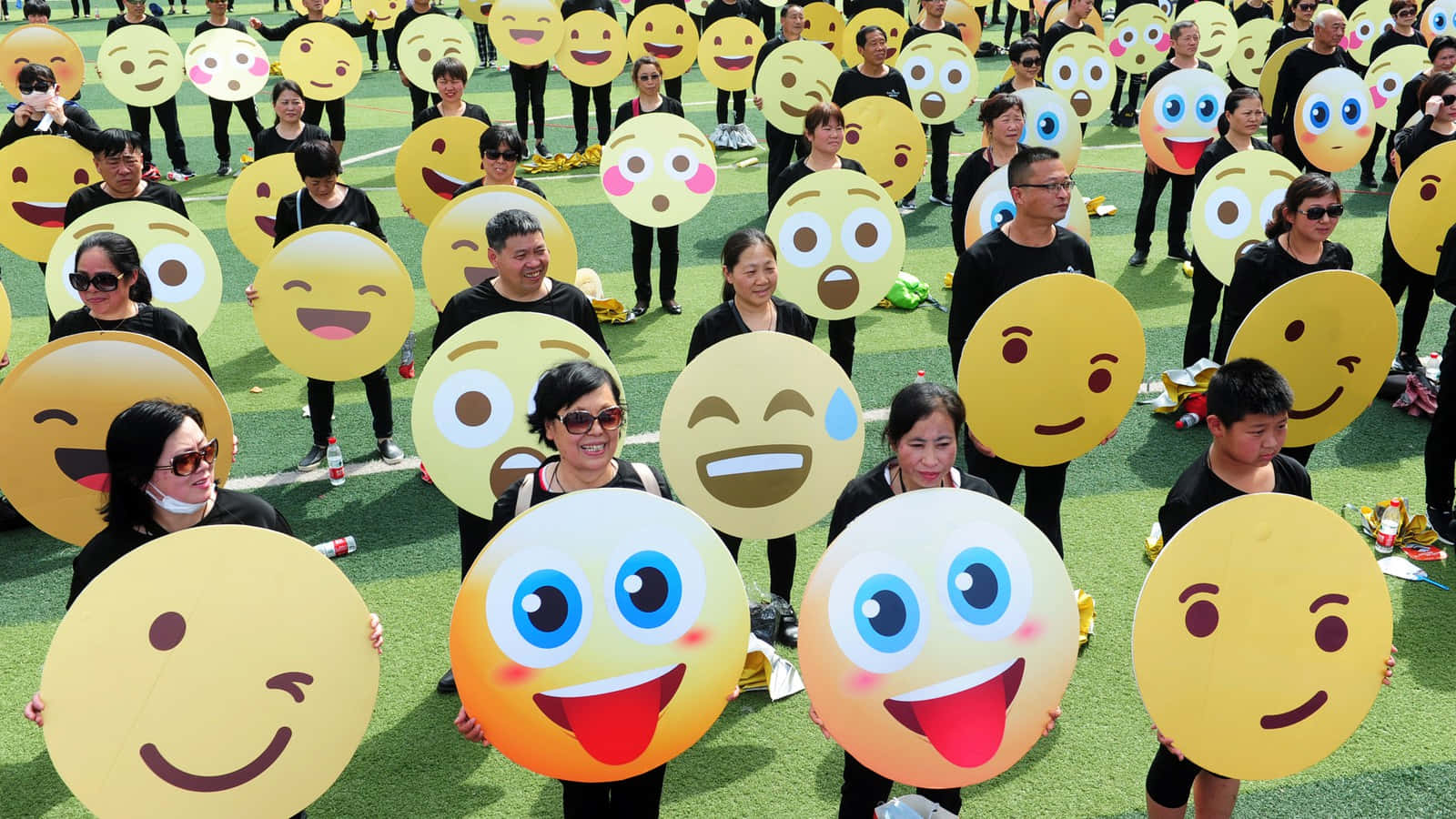 Einegruppe Von Menschen Hält Emojis In Die Höhe.