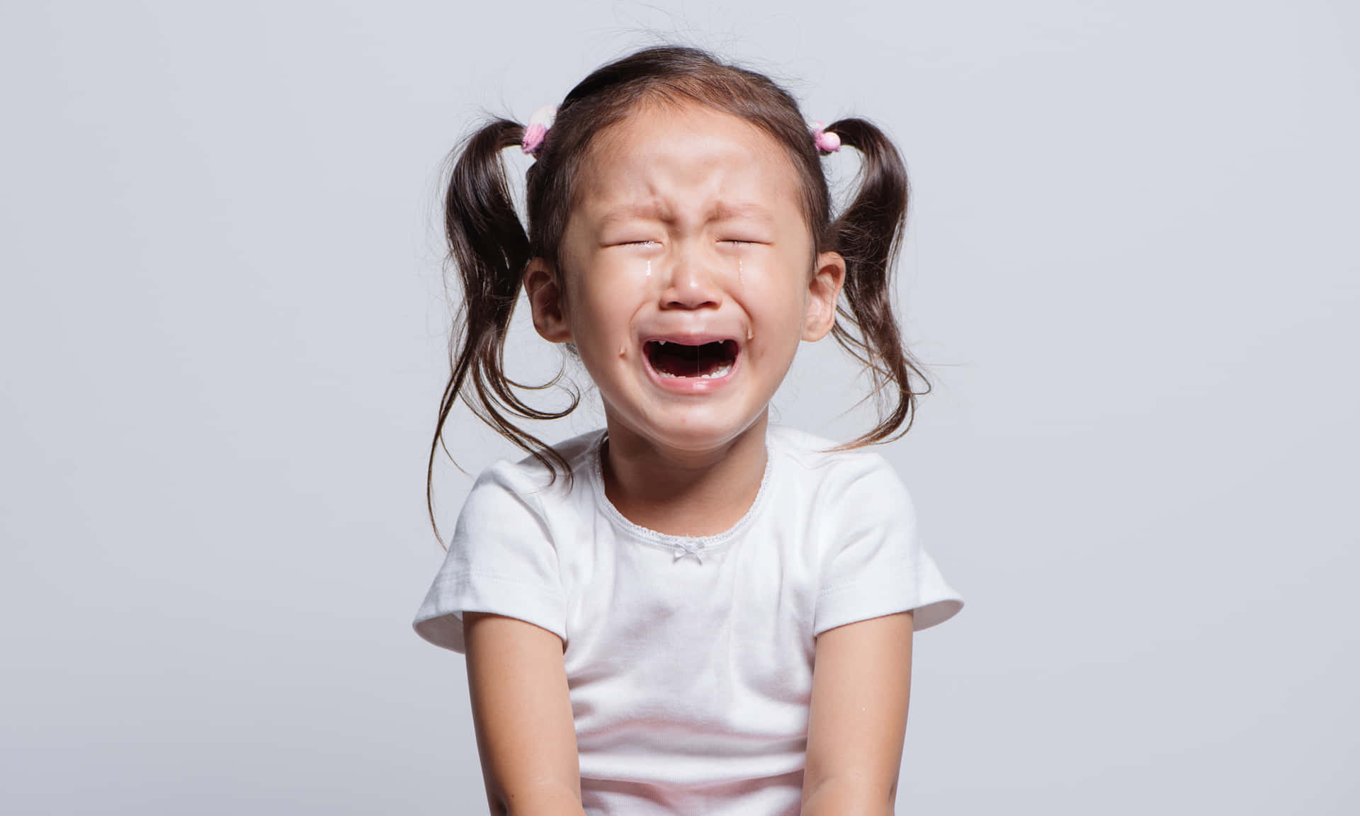 A Little Girl Is Crying On A Gray Background