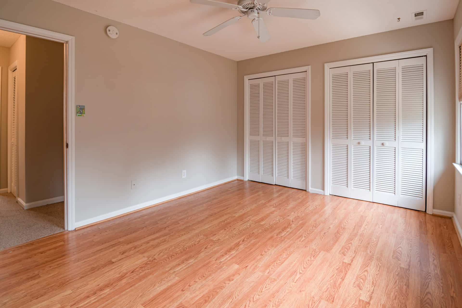 Empty Bedroom With Hardwood Floors And A Ceiling Fan
