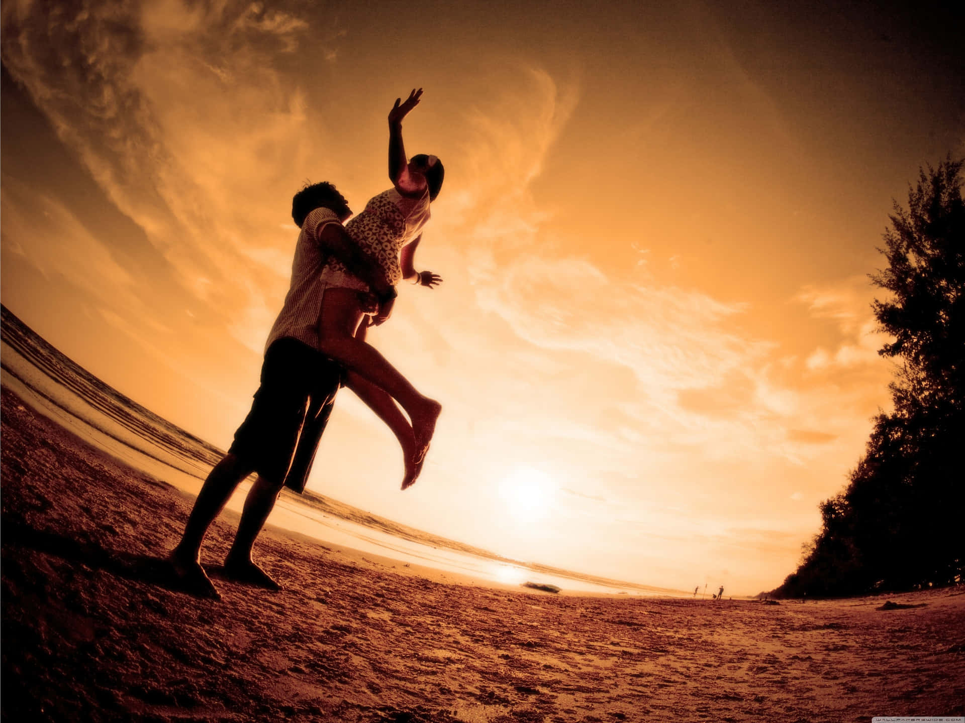 Enamoured Couple Enjoying A Serene Sunset Together Wallpaper
